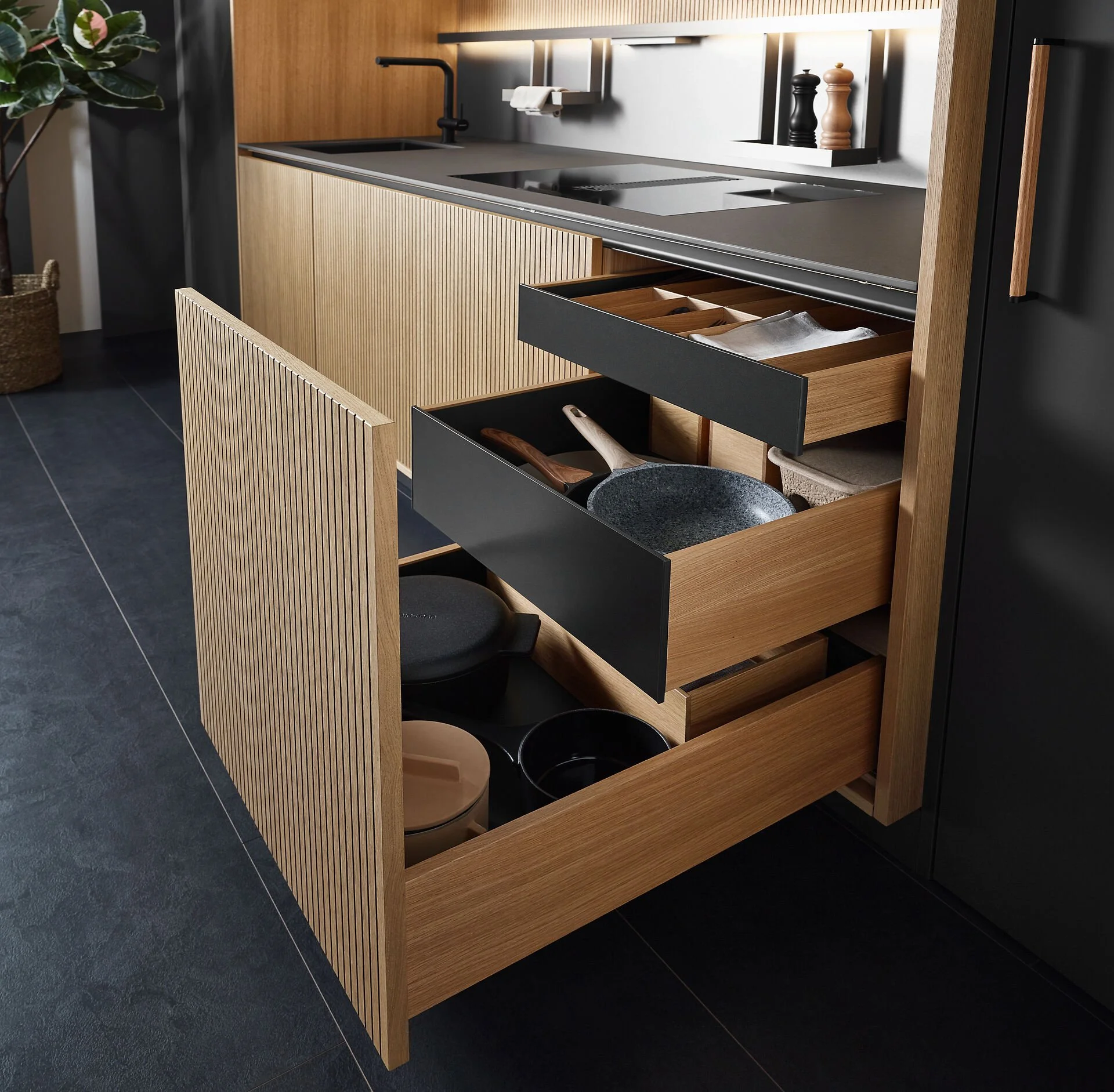 Kastje onder het keukenaanrecht met open lades vol pannen, keukenaccessoires en bestek, vlakbij aanrecht en kookplaat.