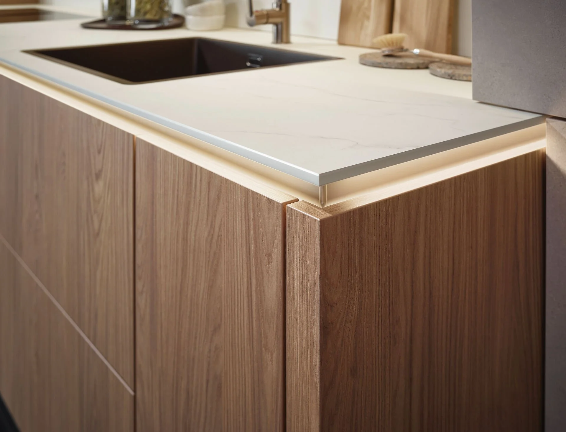 Close-up van een houten keukenkastje met een wit marmeren werkblad en een zwarte gootsteen.