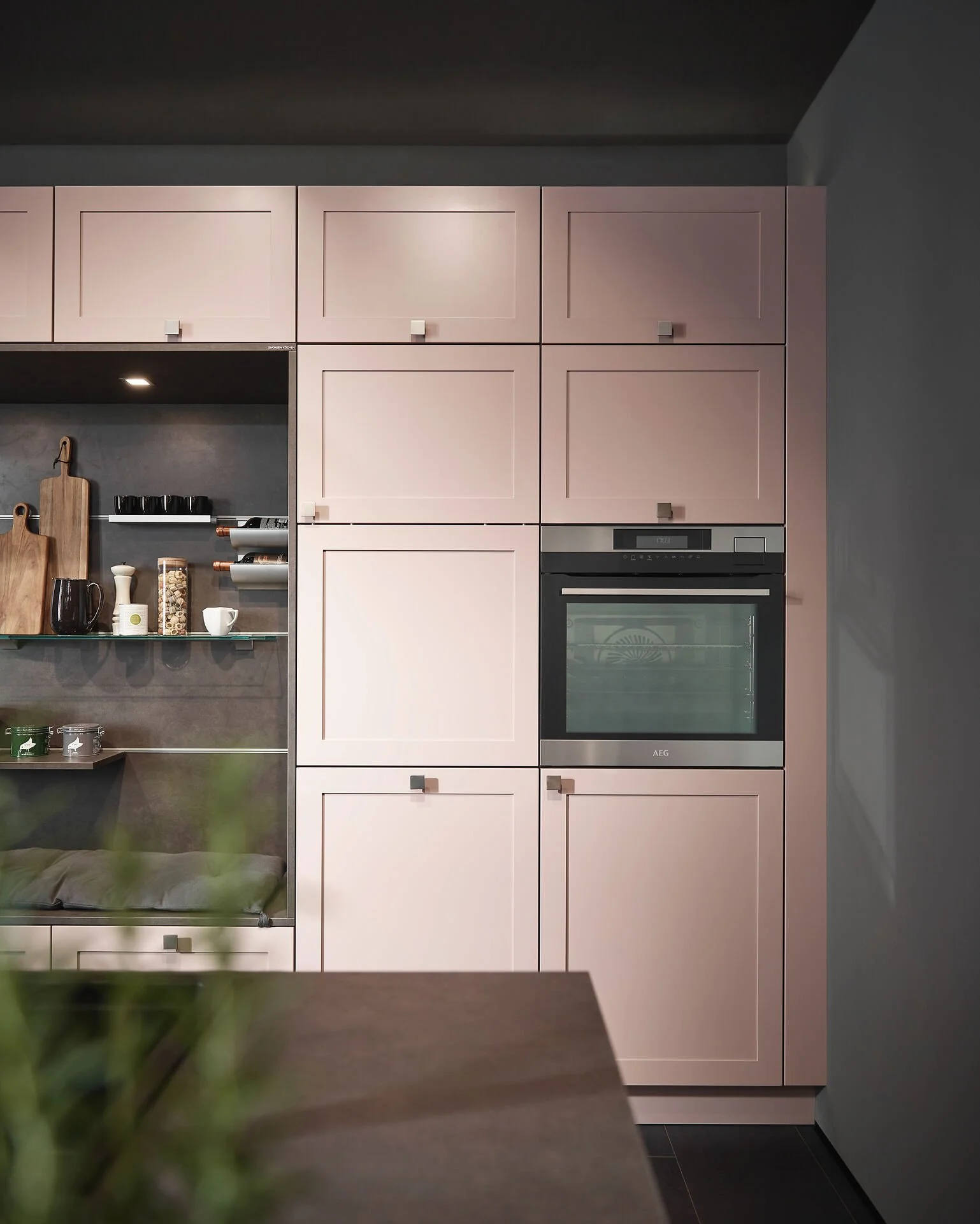 Moderne keuken met ingebouwde oven, lichtroze kasten met kaders, houten snijplank en glazen planken met keukengerei