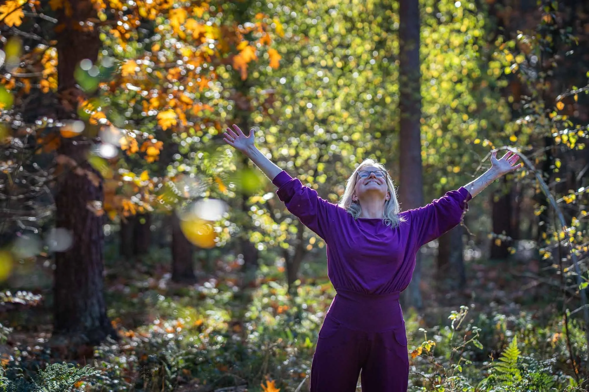 Marieke natuurcoach met armen wijd in het bos, lachend en stralend vanuit haar essentie