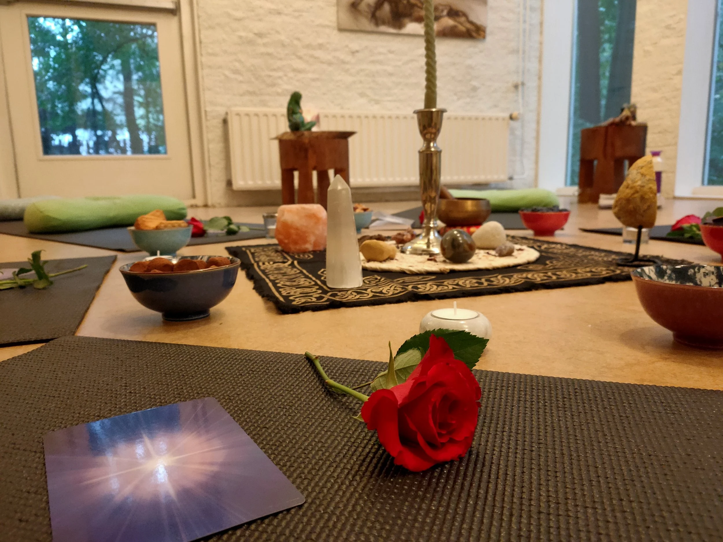 Een mooi ingerichte ruimte met een rode roos, een kaars en diverse decoratieve stenen en voorwerpen, klaar voor een transformatiecirkel.