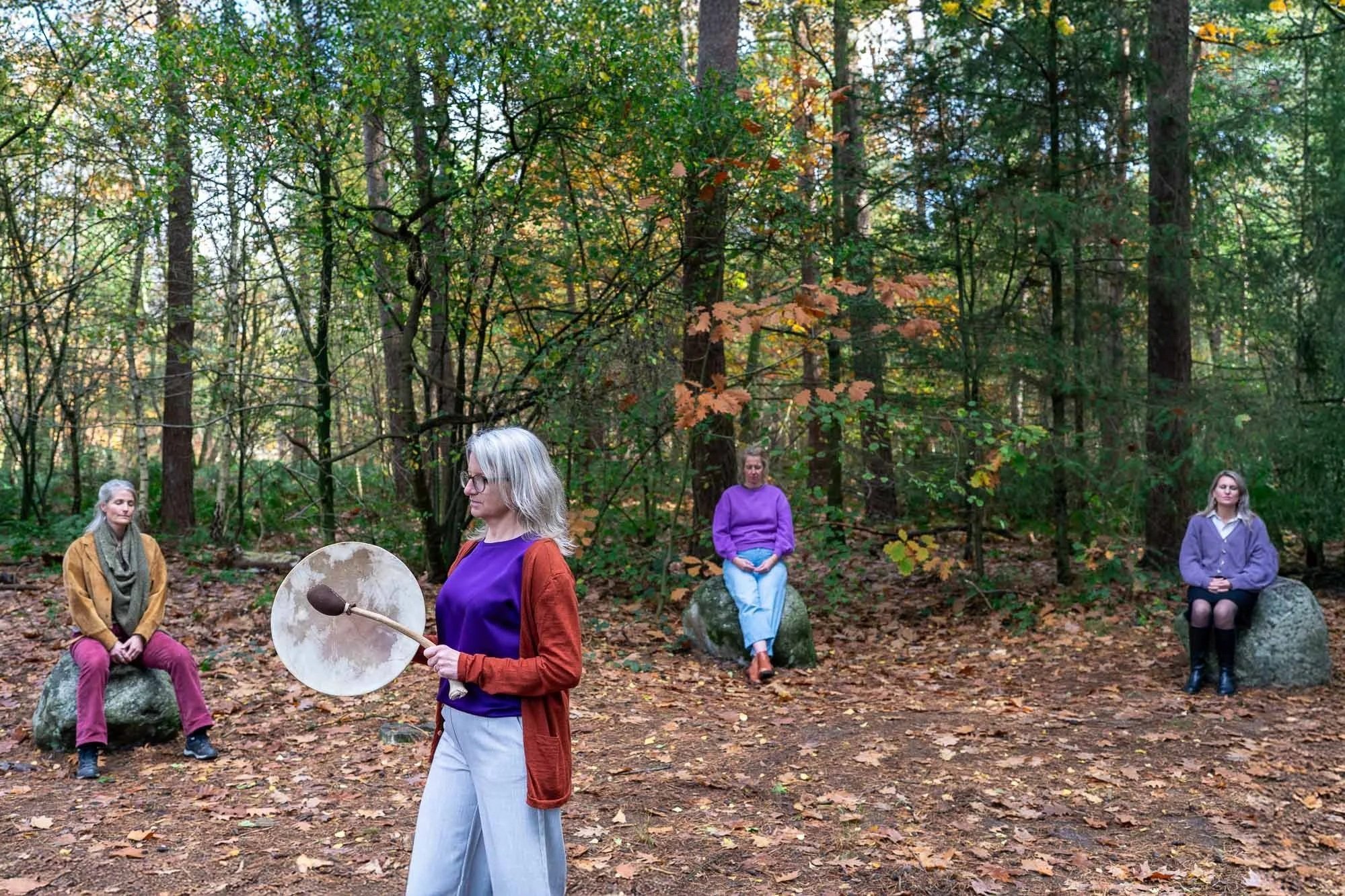 Marieke natuurcoach begeleidt groepscoaching met sjamanistische drum tussen de bomen