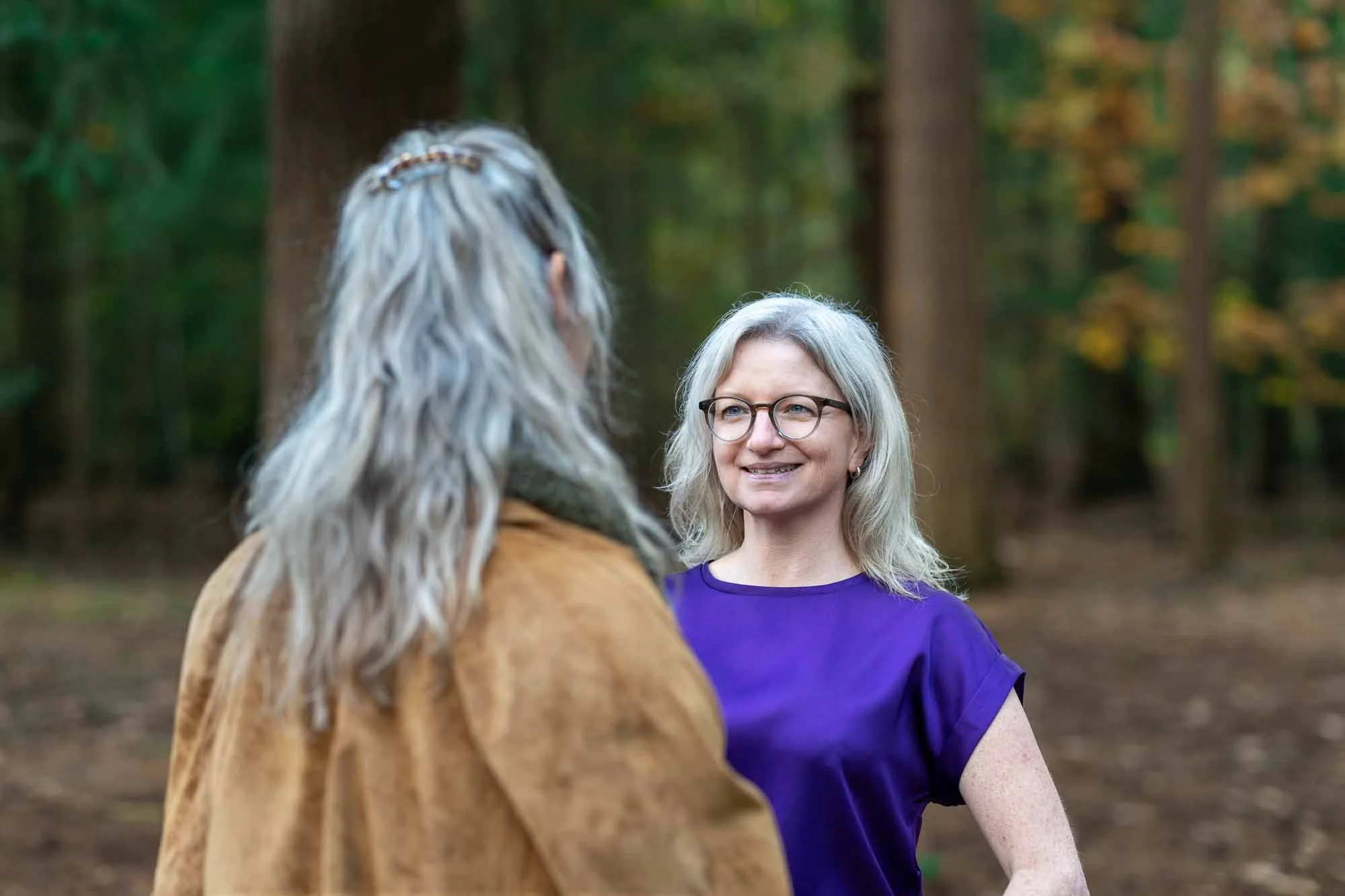 Marieke natuurcoach kijkt vriendelijk naar klant tijdens coaching in het bos