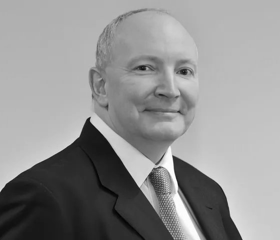 Black and white portrait of a middle-aged man in a suit and tie, smiling.