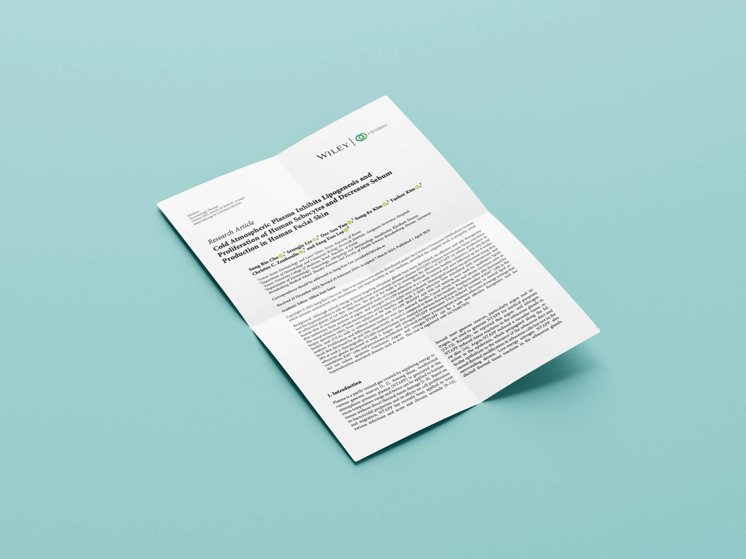 A scientific research article on a white sheet of paper against a teal background, with the title and author details visible.