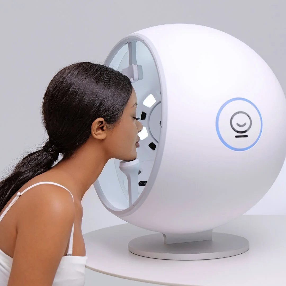 Woman undergoing a medical or cosmetic imaging procedure with a large, white, circular machine.