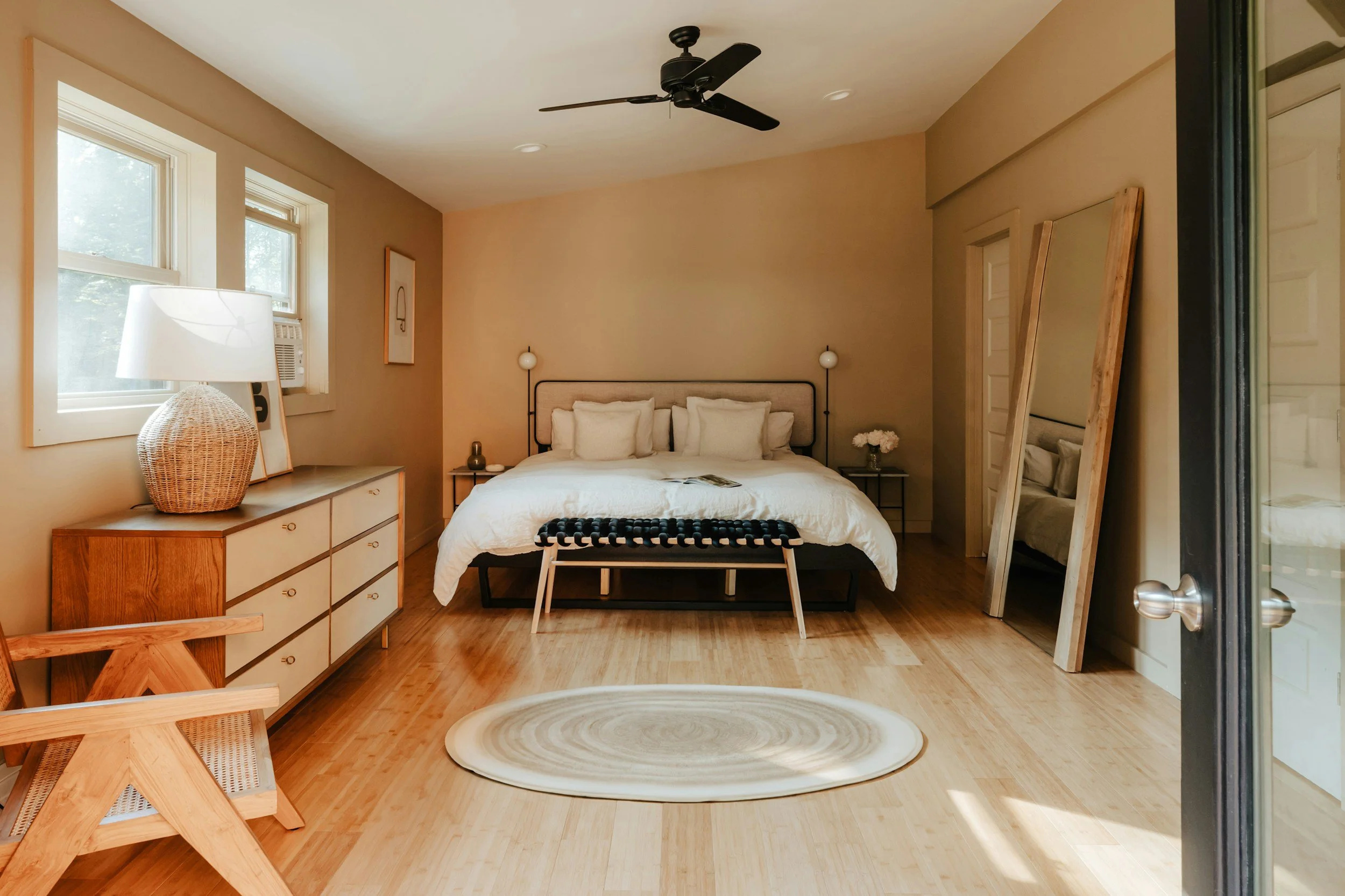 Chambre dans location meublé épurée avec lit double, tapis et décorations.