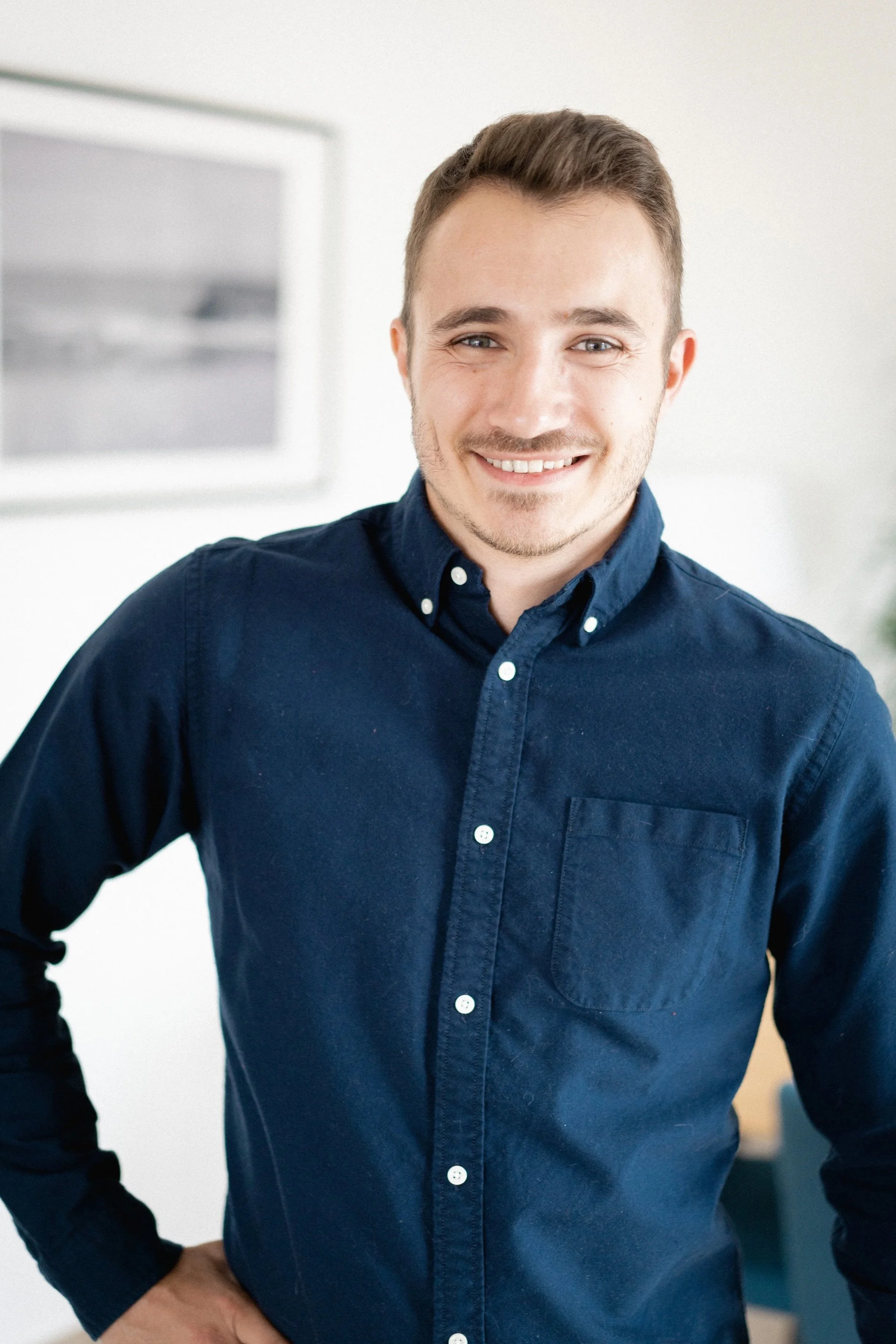 Homme souriant portant une chemise bleue dans une pièce moderne