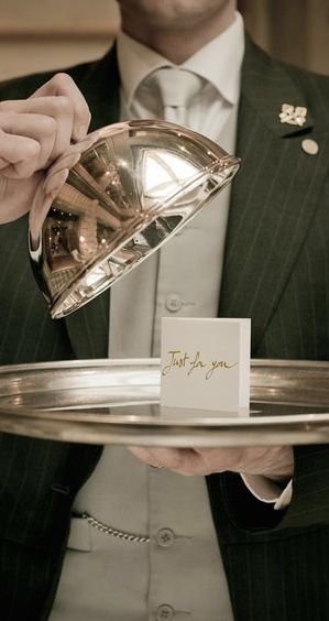 Luxury service concept with a butler presenting a silver tray and a personalized note — symbolizing exclusivity and premium brand experience.