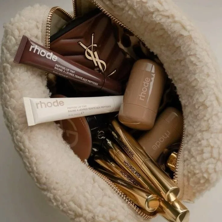 Flat lay of Rhode skincare and luxury beauty products inside a beige pouch, minimalist beauty branding and consumer aesthetic.