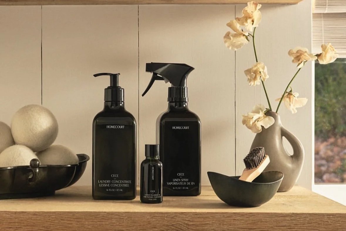 Homecourt luxury homecare products styled in a minimalist interior with wooden shelves, neutral home decor, and matte black bottles.