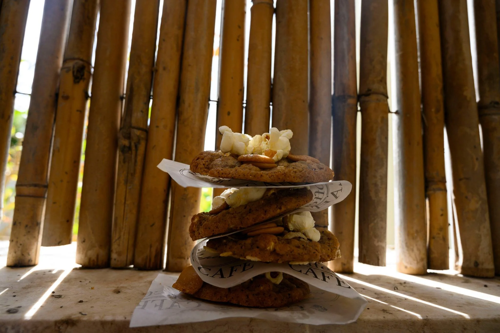 עוגיות פופקורן ובייגלה מוערמות על רקע במבוק, כמו מגדל חטיפים קטן שנבנה במיוחד בשביל אור אחר הצהריים הזהוב