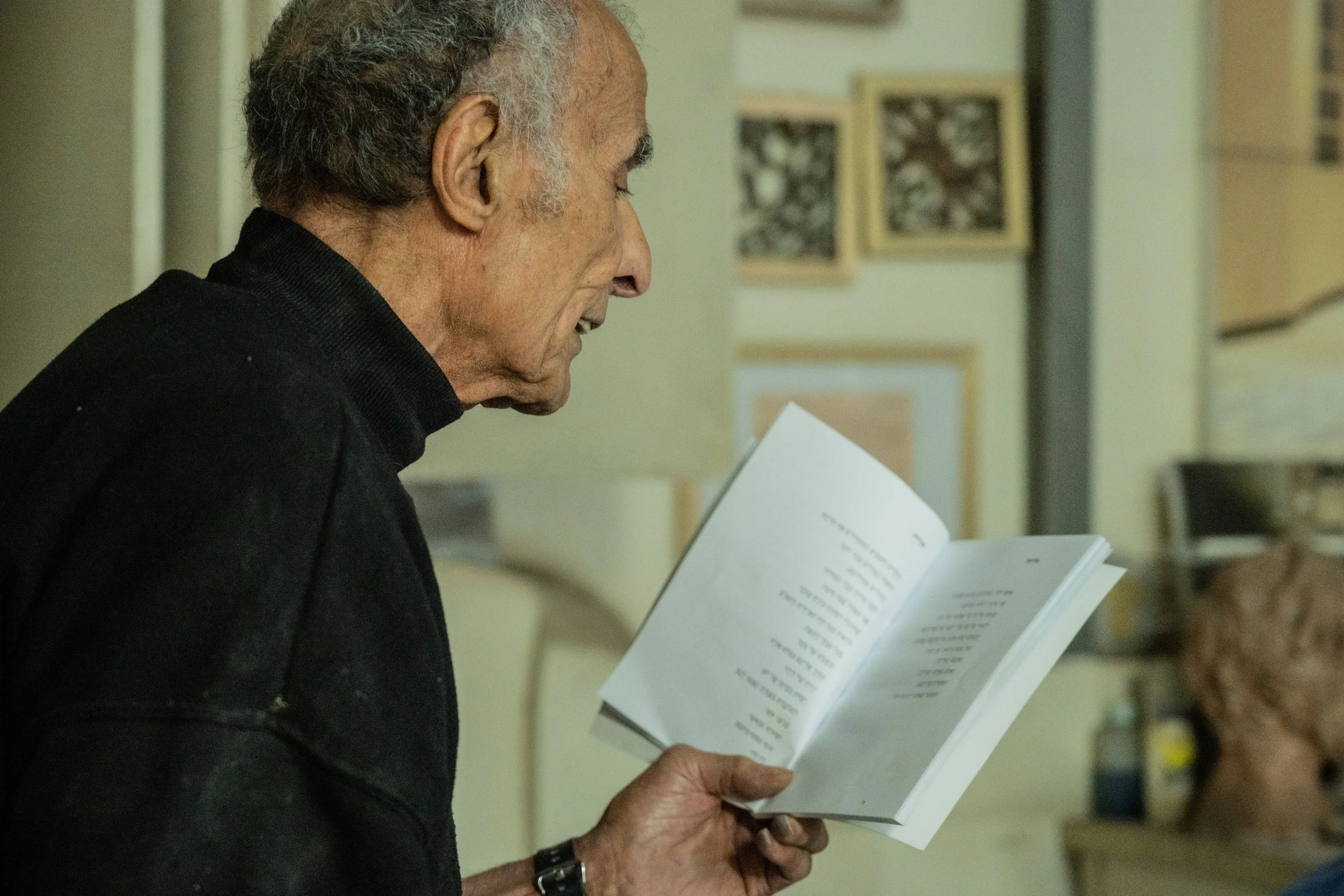 Side profile of tile maker Avner Gluska holding and reading from printed pages