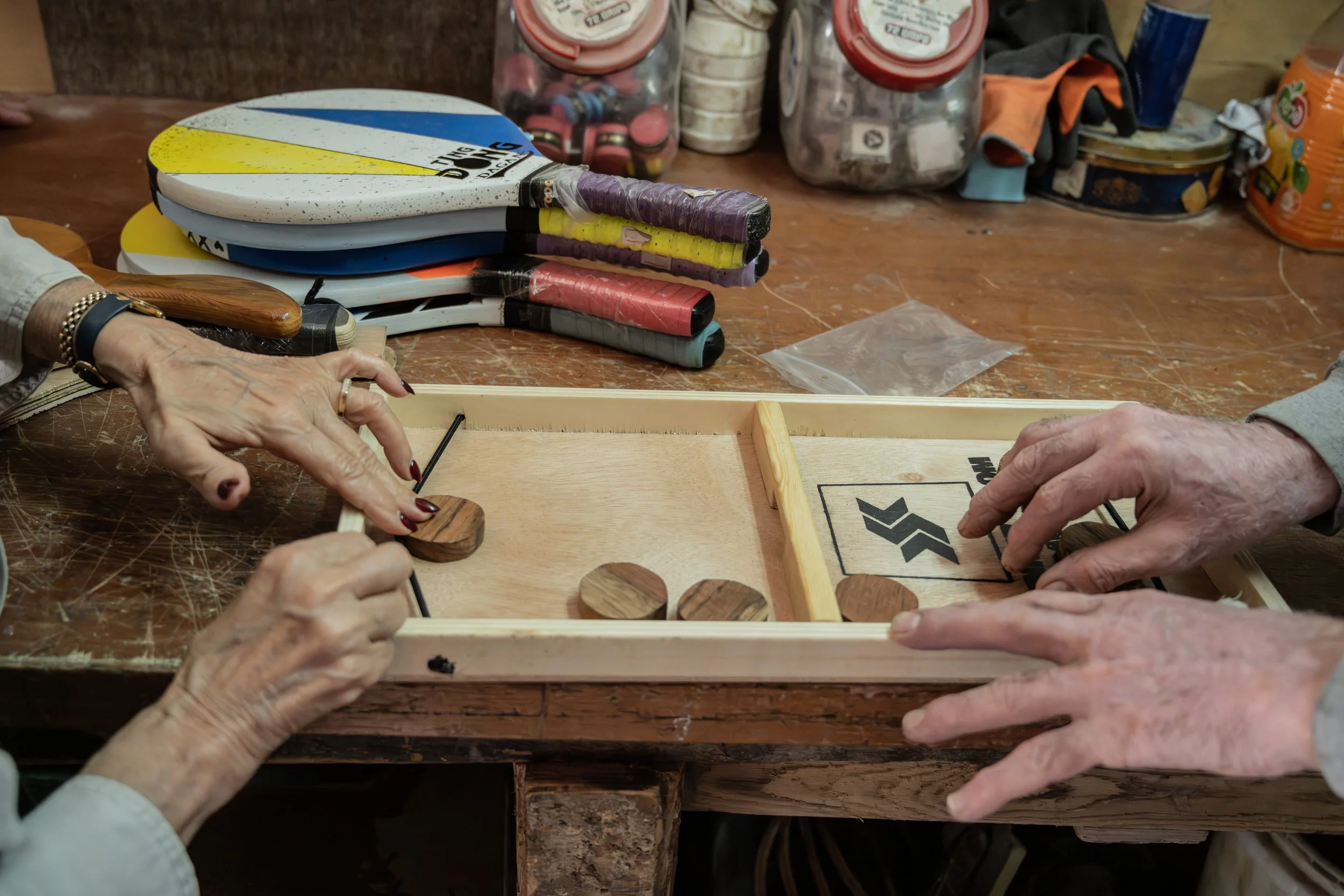 Two pairs of hands playing a wooden board game