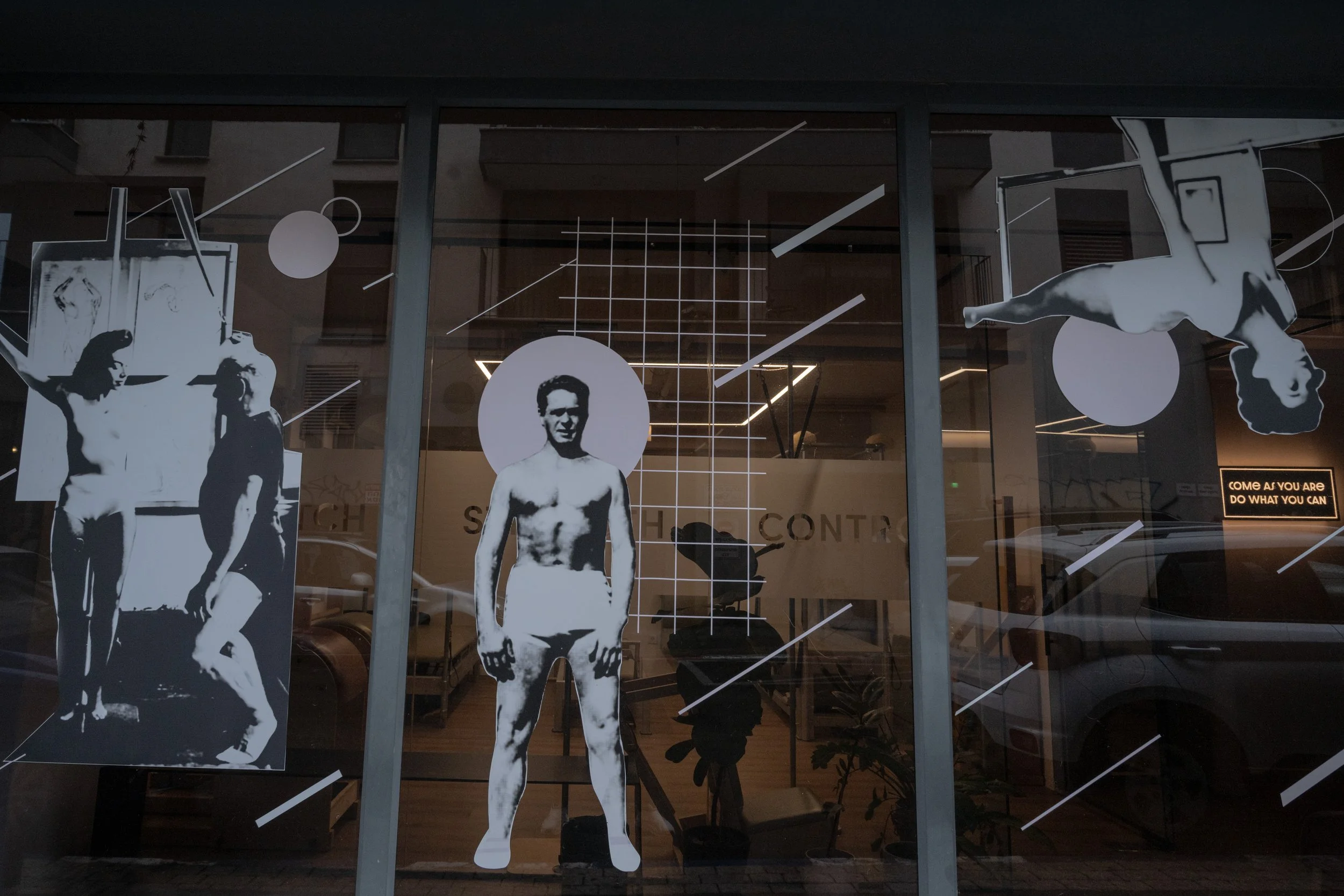 דמויות שחור־לבן גדולות של ספורטאים מודבקות על חלון סטודיו מודרני בתל אביבב