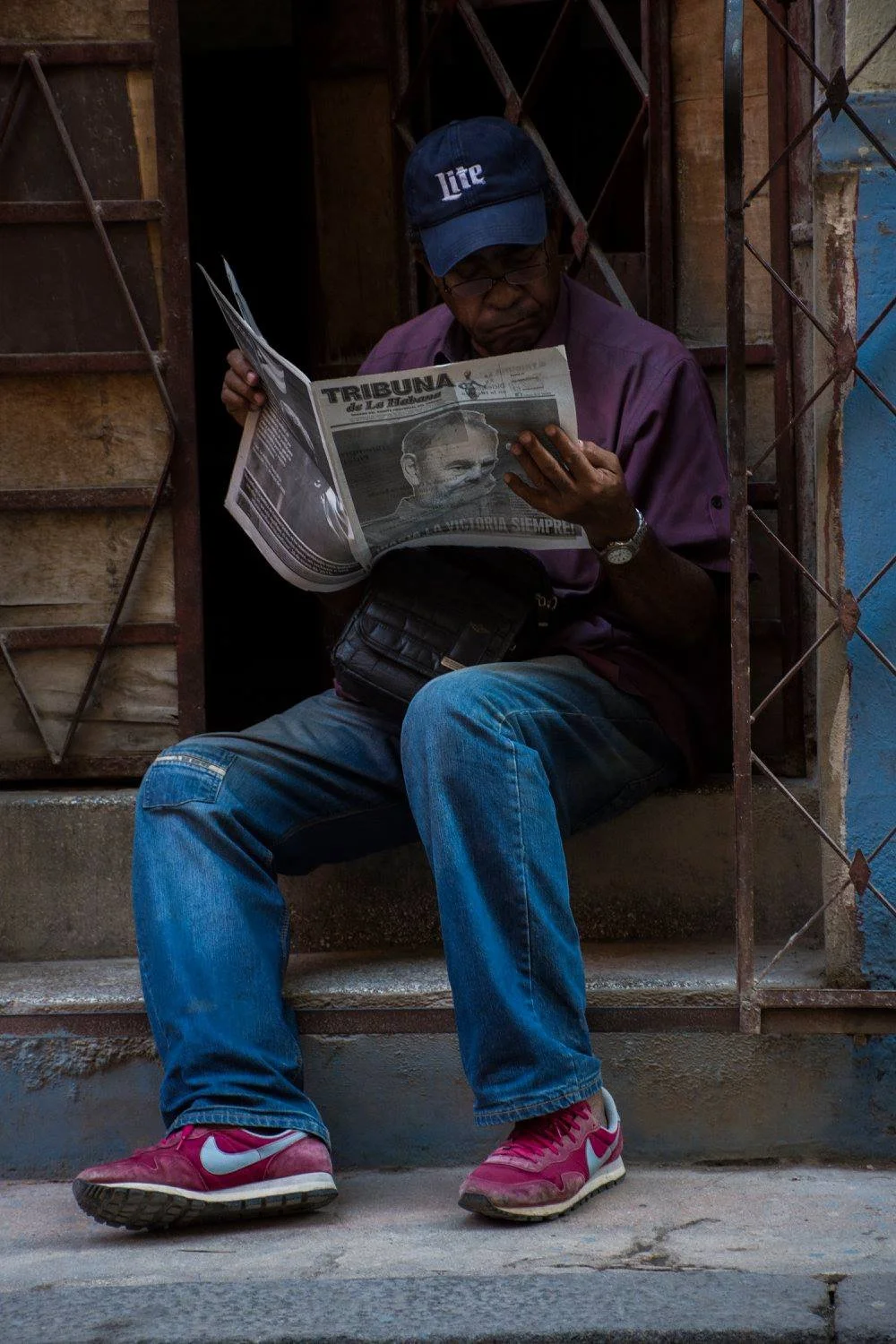 גבר יושב על מדרגה וקורא את מהדורת פידל קסטרו של Tribuna de La Habana