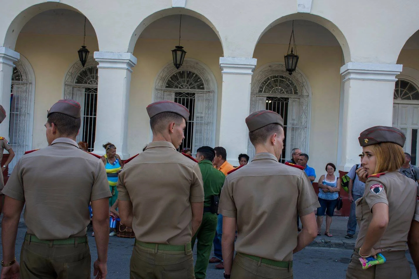 חיילים במדי חאקי מתקהלים מתחת לארקדה בזמן שתושבי העיר צופים מהצד