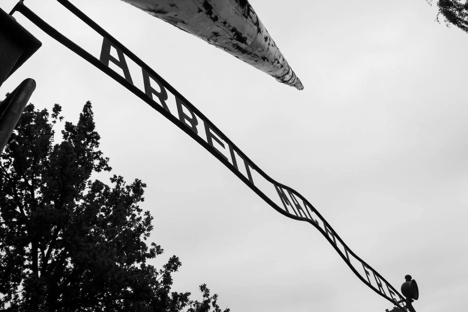 שער "Arbeit macht frei" בשחור־לבן בכניסה לאושוויץ