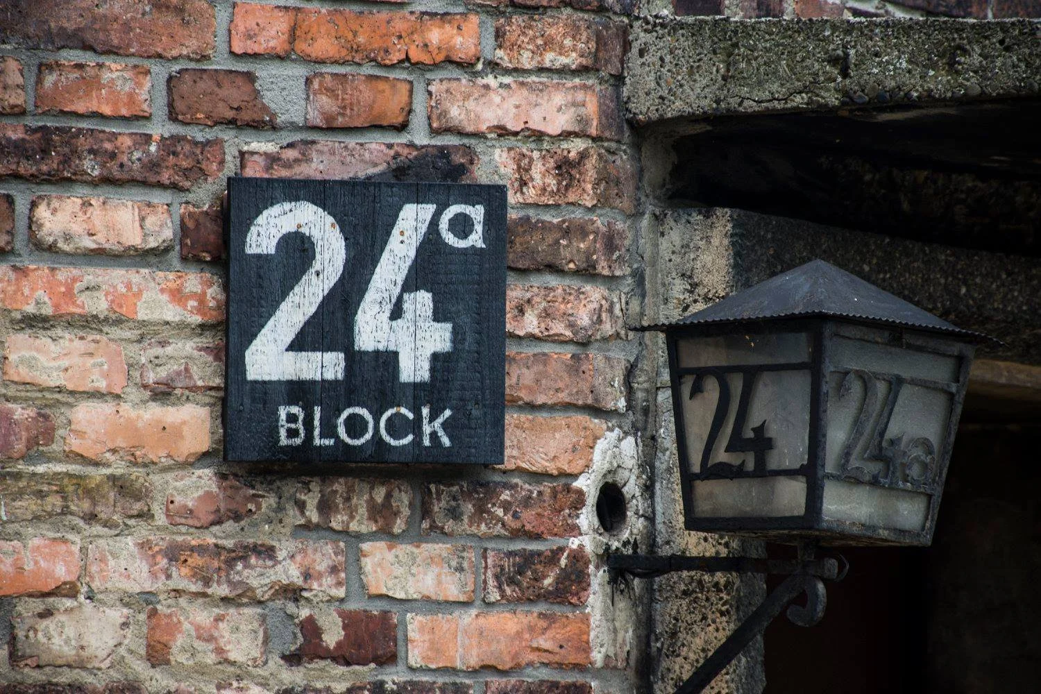 שלט Block 24a ועמוד פנס על קיר לבנים באושוויץ