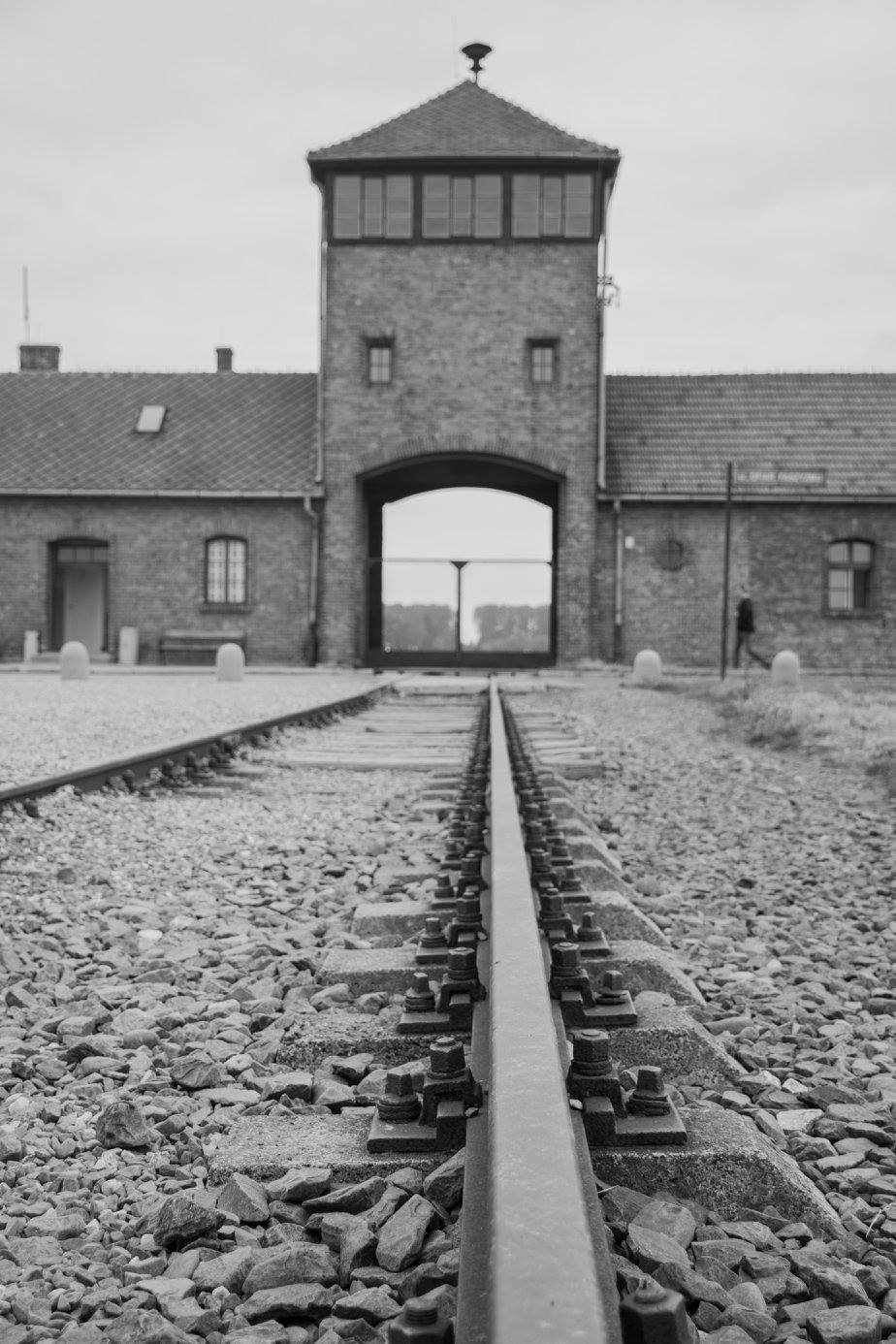 מסילות רכבת מובילות דרך שער אושוויץ־בירקנאו בצילום מונוכרום