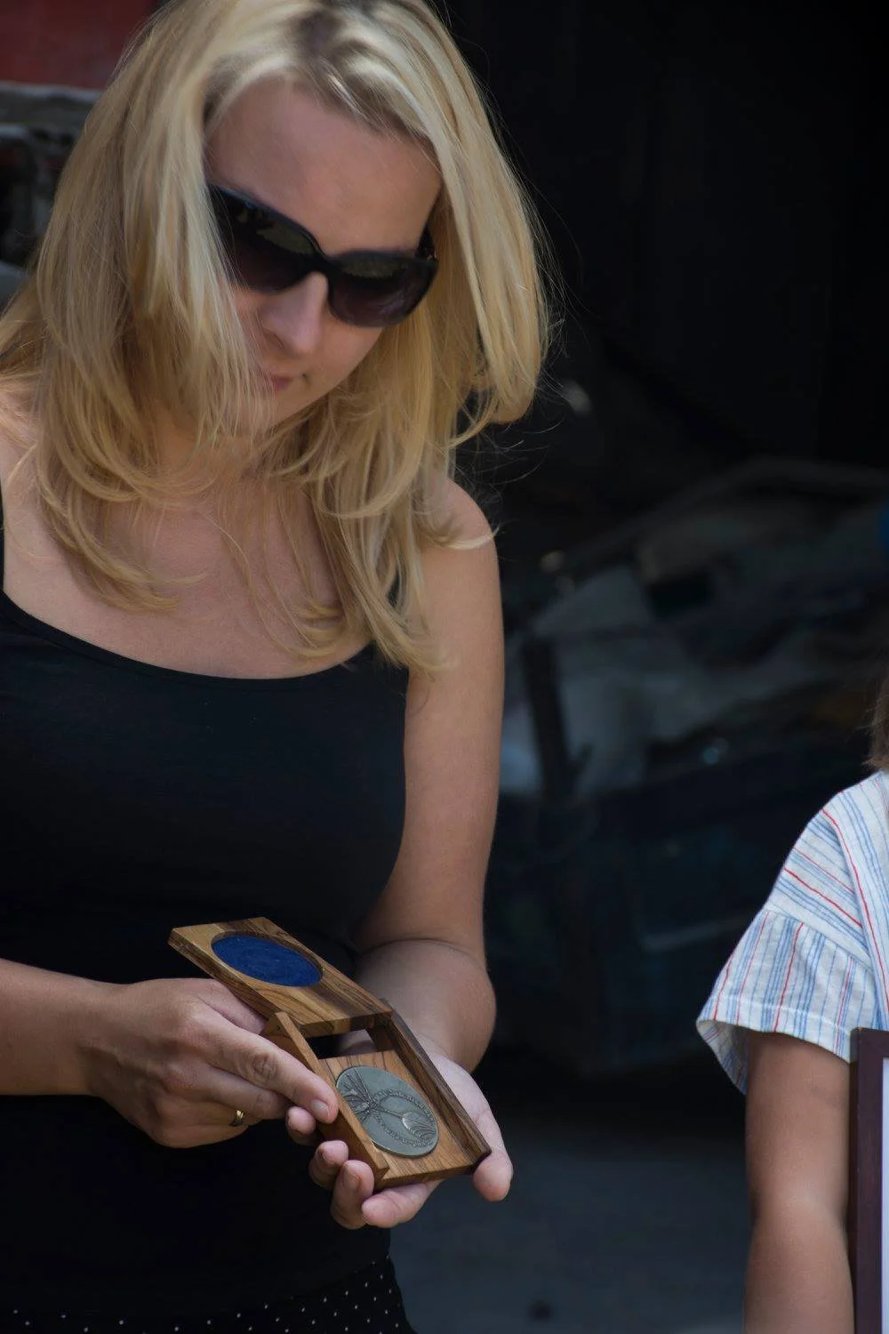 אישה בוחנת מדליית חסיד אומות העולם וקופסתה במהלך טקס הוקרה