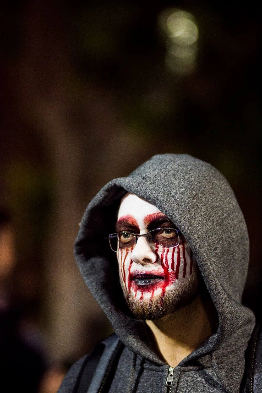 גבר עם קפוצ׳ון ומשקפיים באיפור זומבי נוזל באדום ולבן