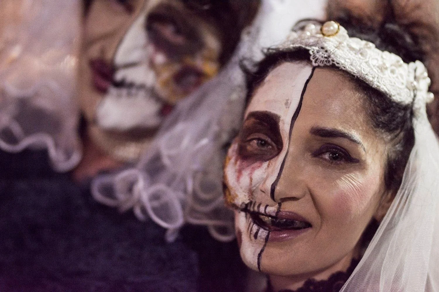 כלה מחופשת עם חצי פנים באיפור גולגולת והינומת חתונה מביטה למצלמה