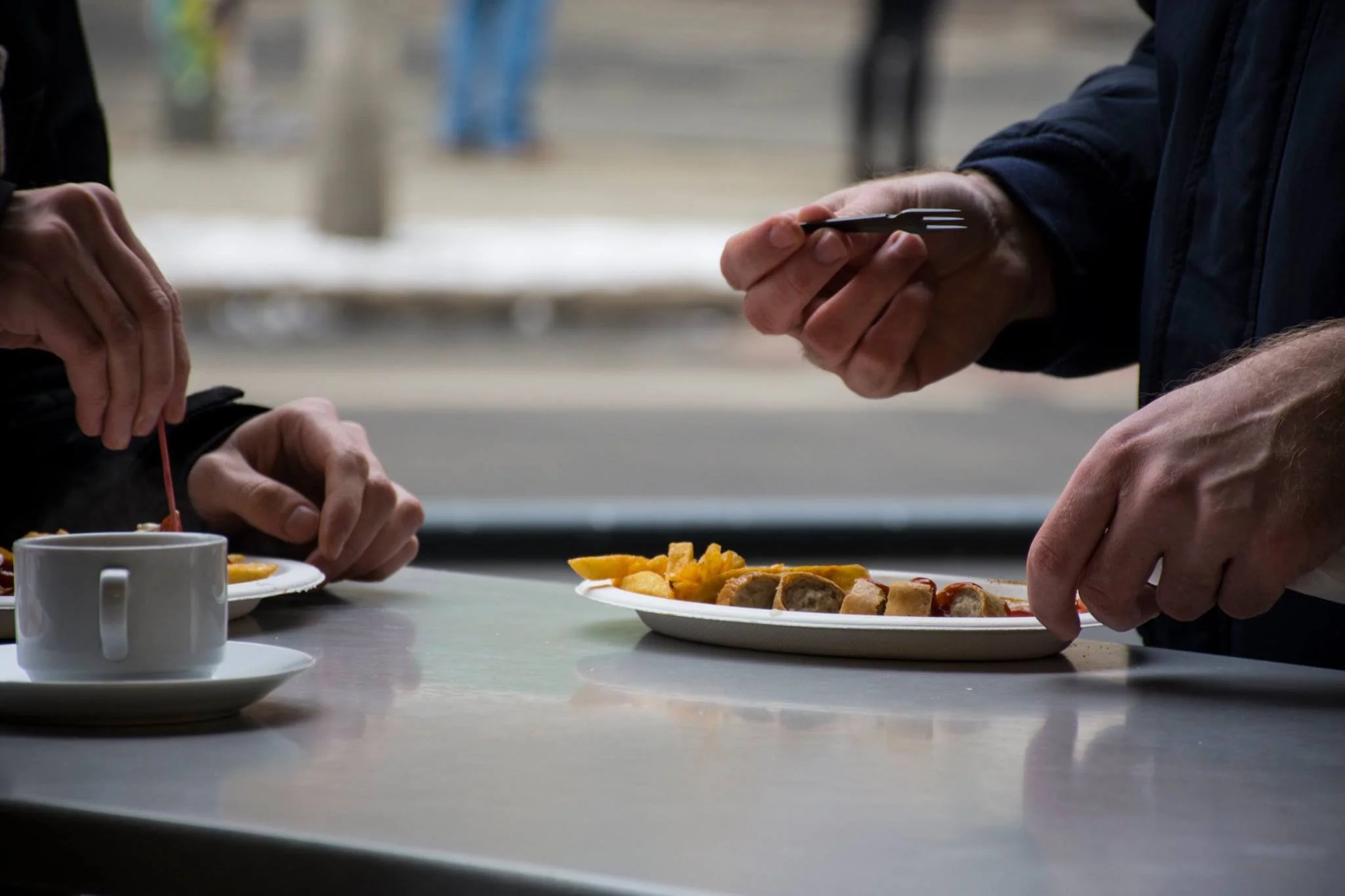 תקריב ידיים אוכלות בשולחן בית קפה עם כוס קפה וצלחת בברלין