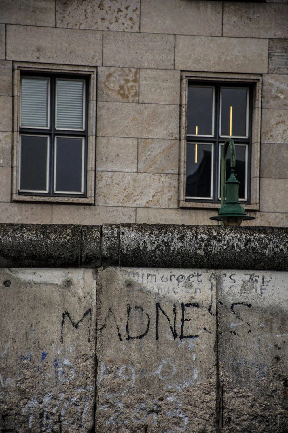 קטע מחומת ברלין עם גרפיטי המילה MADNESS וחלונות דירות ברקע