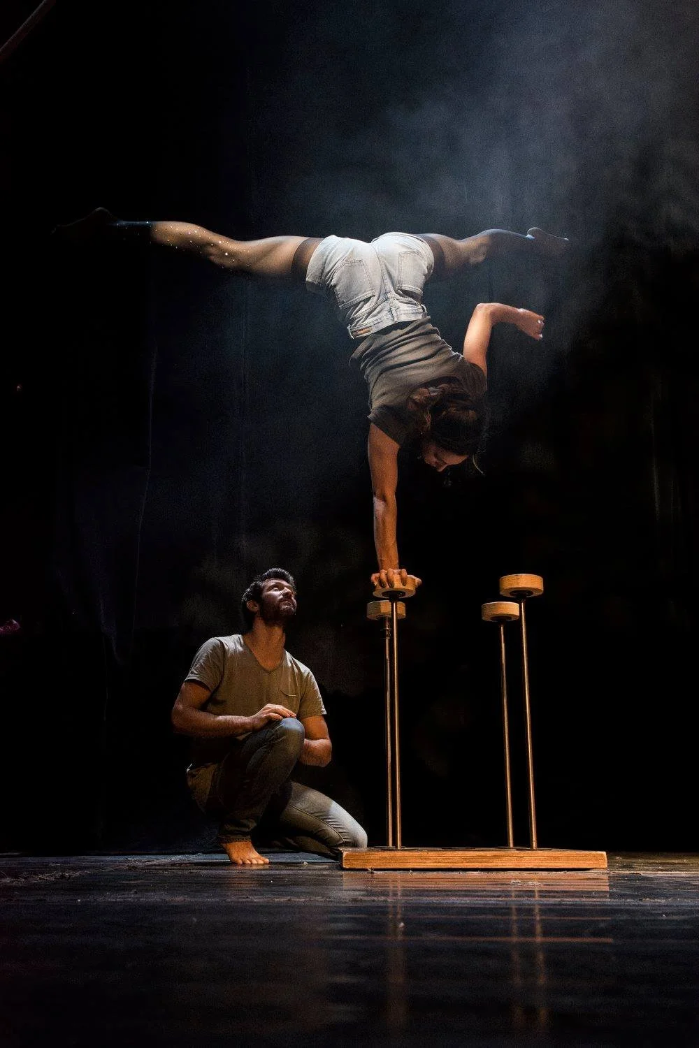 עמידת יד אחת על קנים בעוד פרטנר מאבטח מתחת בתוך עשן במה