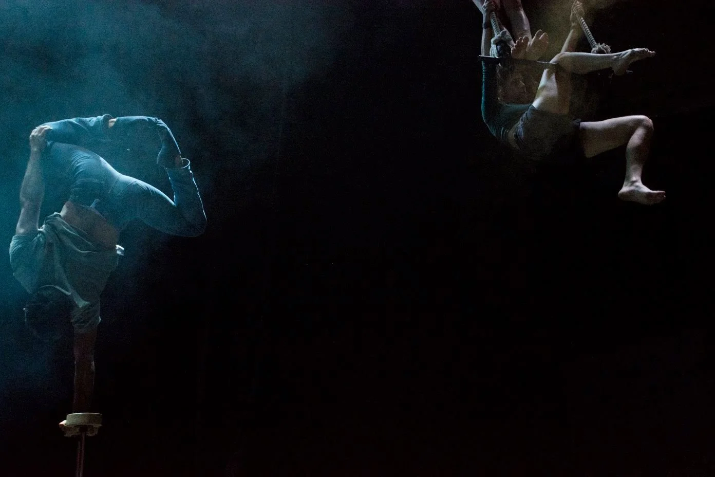 זוג אקרובטים מרחפים באוויר על רקע שחור ועשן