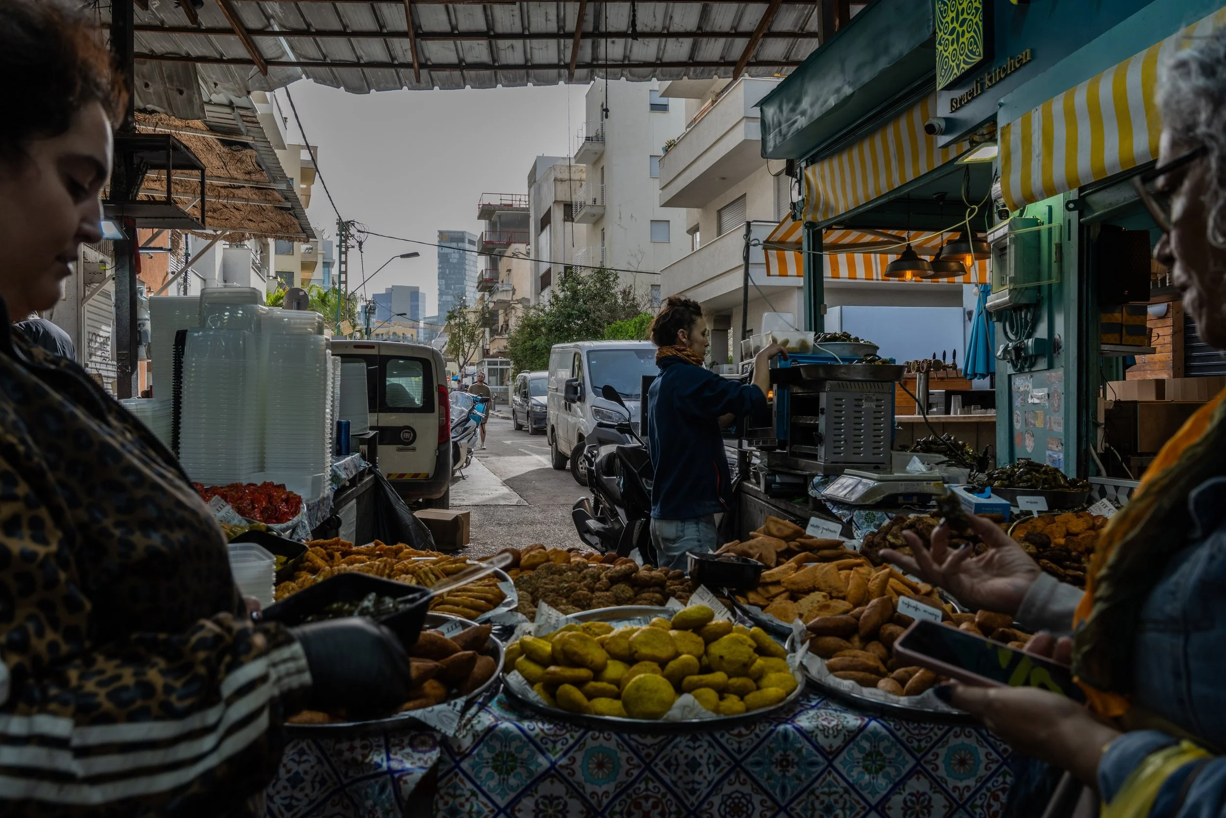 Two women preparing street food at a busy stall in Carmel Market
