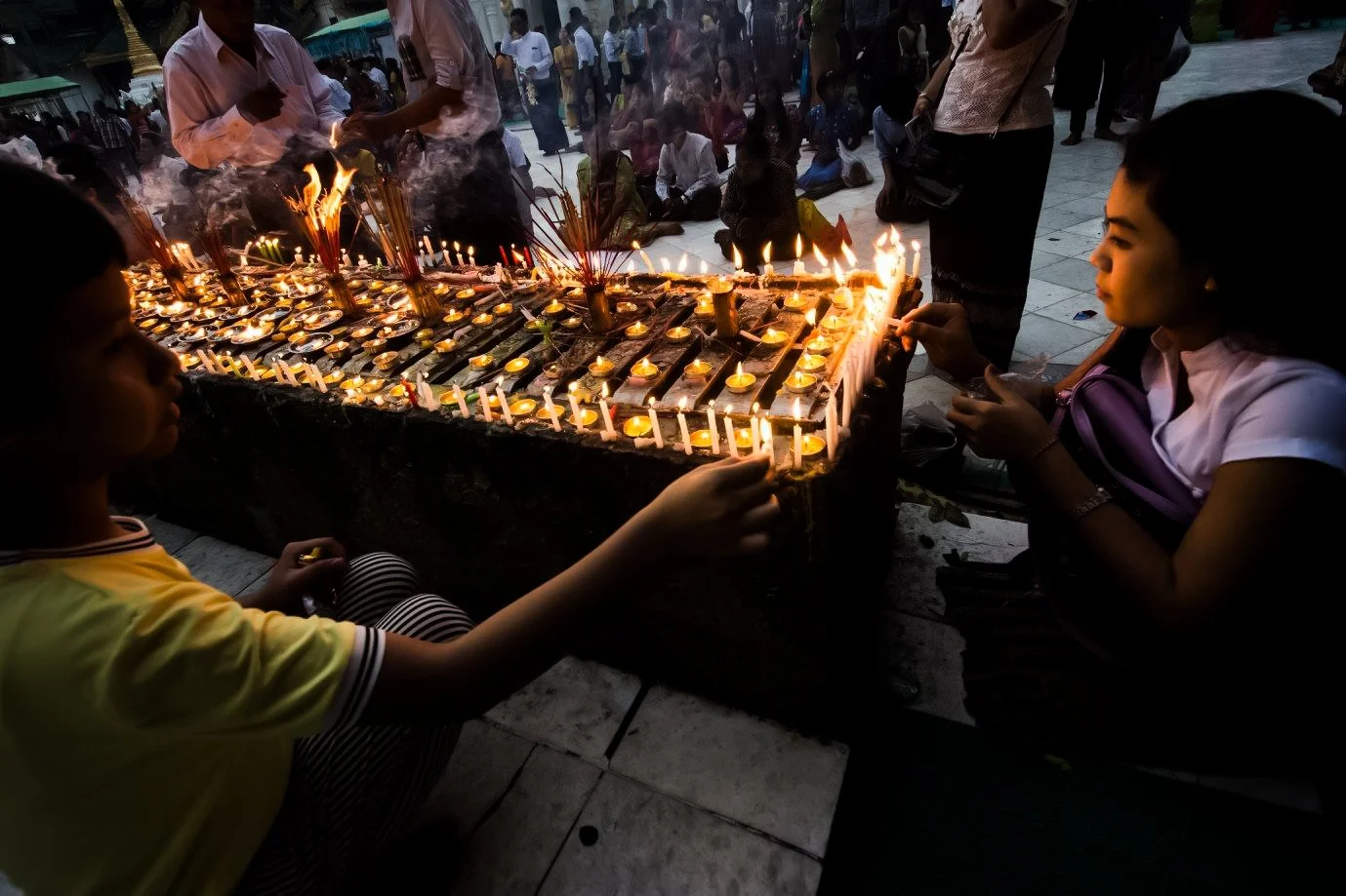 Women and children gathered around a large candle stand during the Festival of Lights in Myanmar
