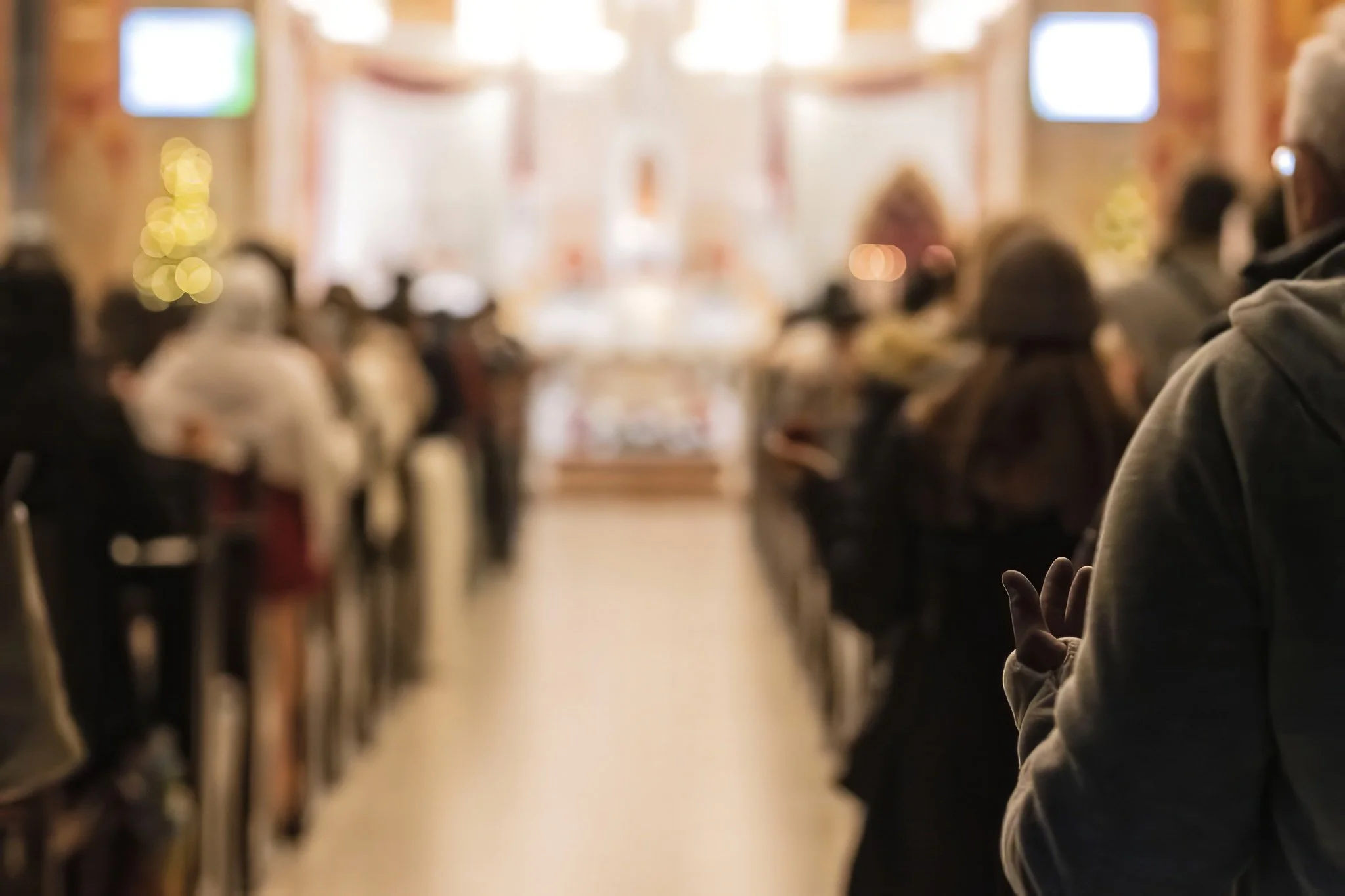 View down a church aisle during a Christmas service in Jaffa, with worshippers seated in soft warm light
