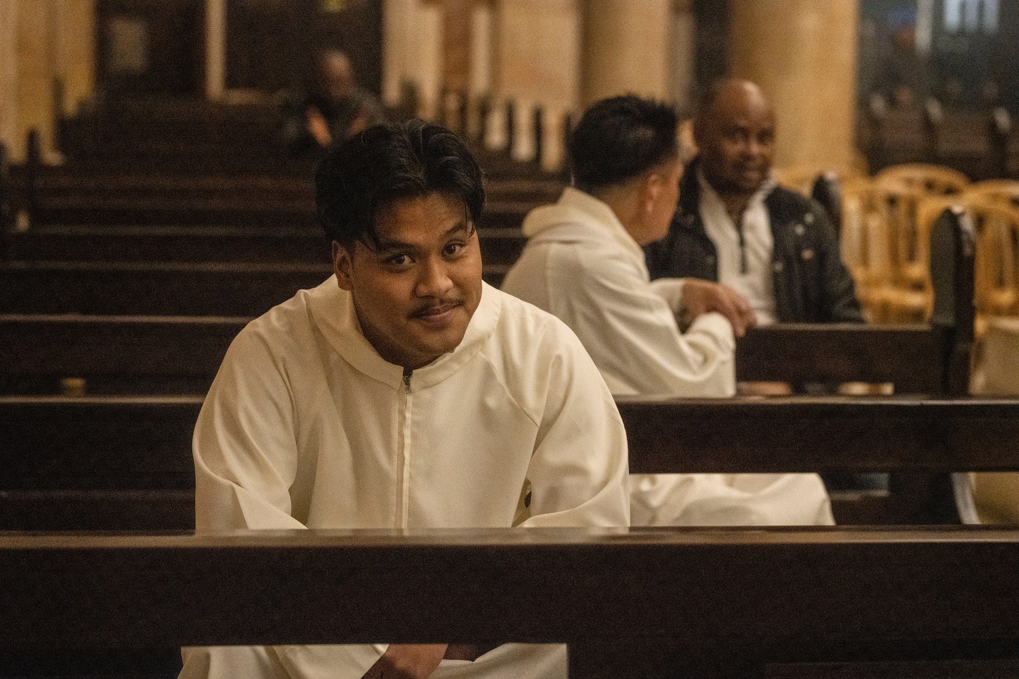 Young man seated in a church pew during a Christmas gathering in Jaffa, looking toward the camera