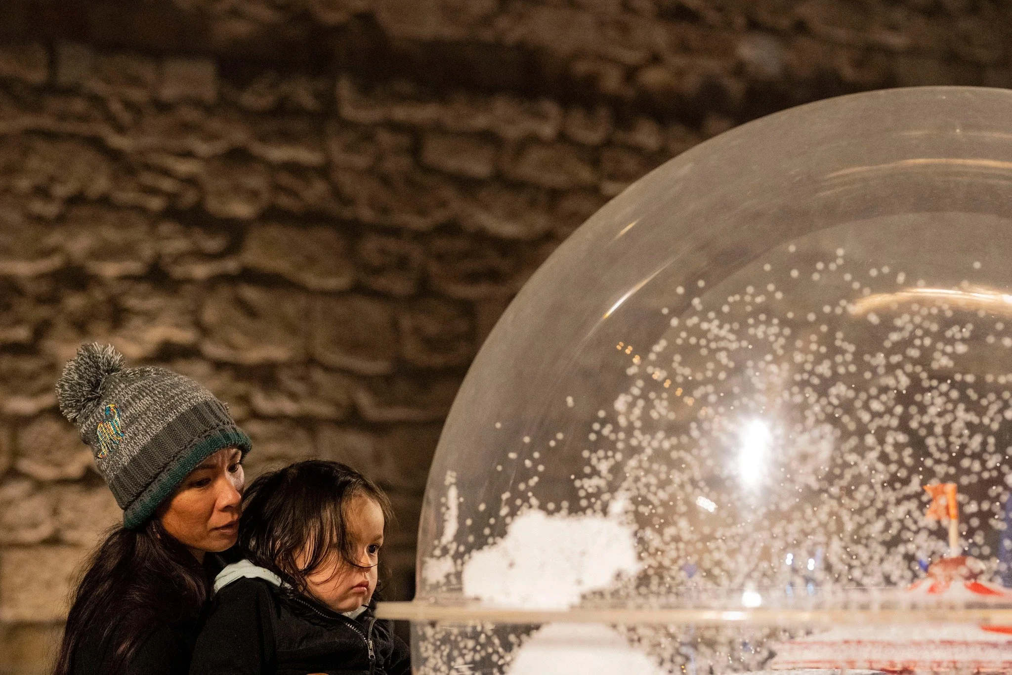 Mother and child beside a transparent holiday display sphere during Christmas celebrations in Jaffa