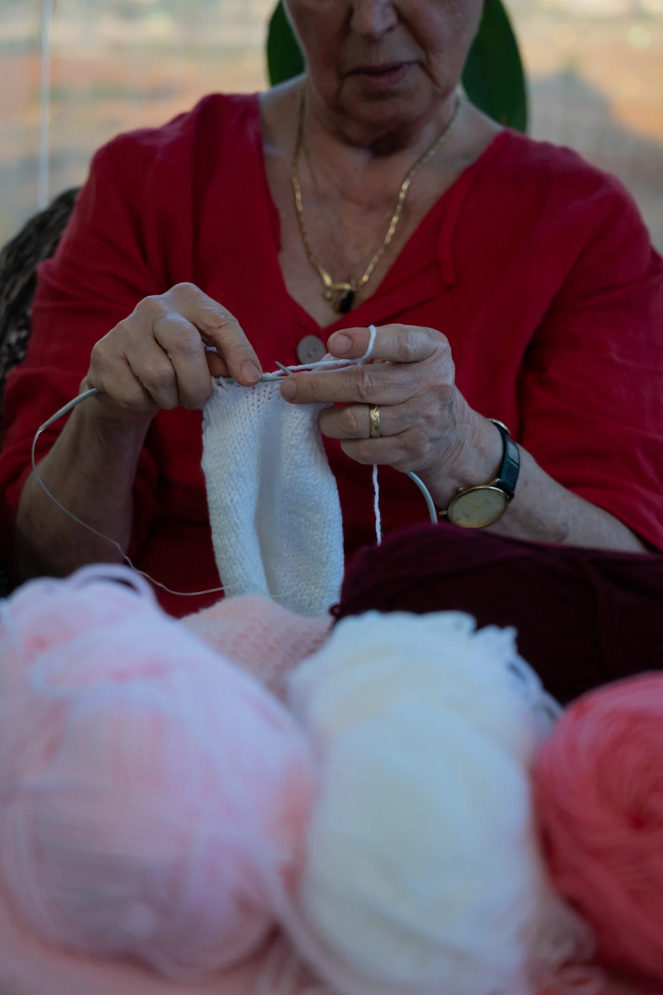 ידיים של אישה סורגות סוודר לבן קטן במסרגות מתכת