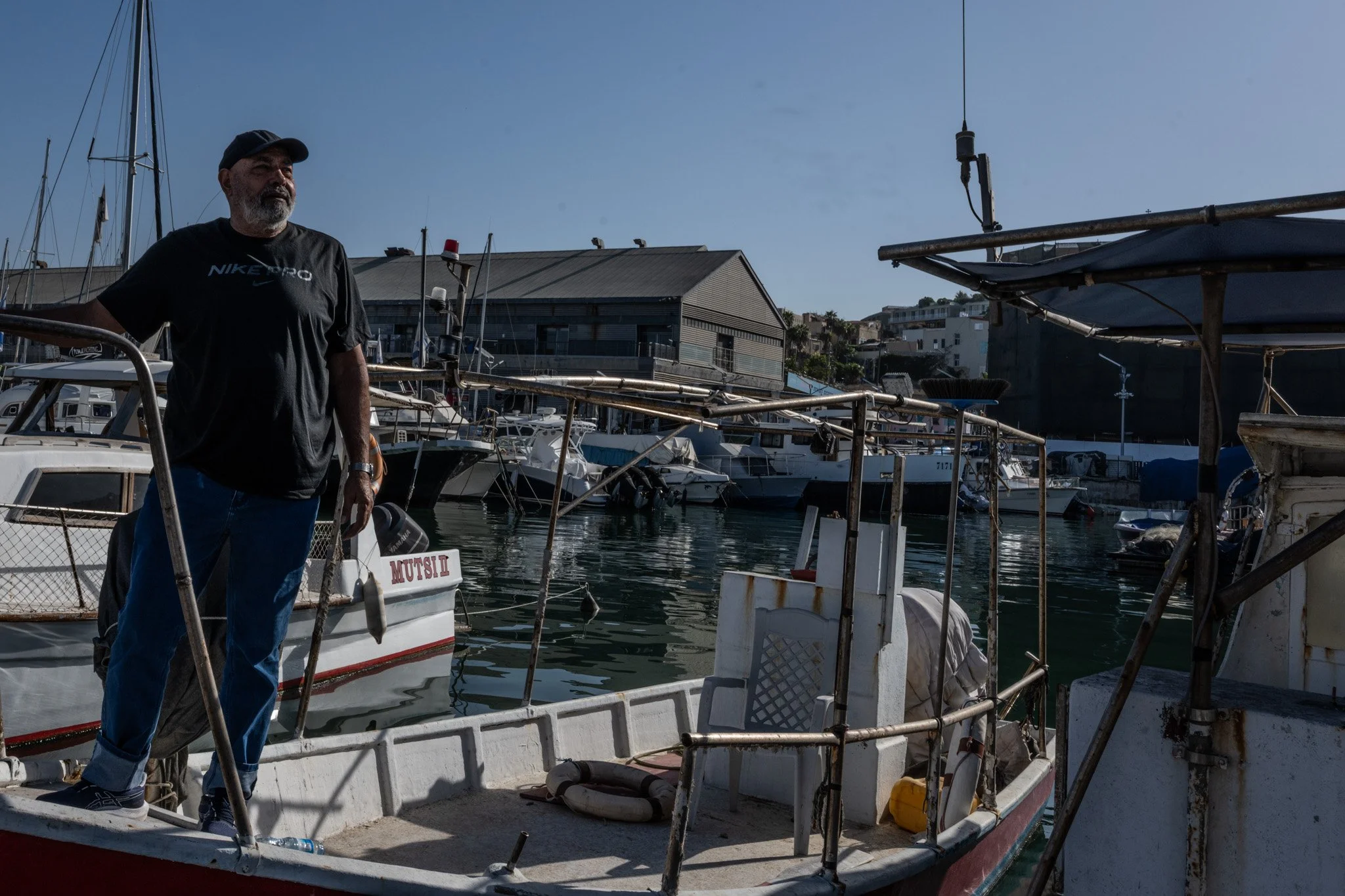 קפטן על הסיפון שלו, העיניים אל המים, מחזיק במבטו עשרות שנים של גאות ושפל