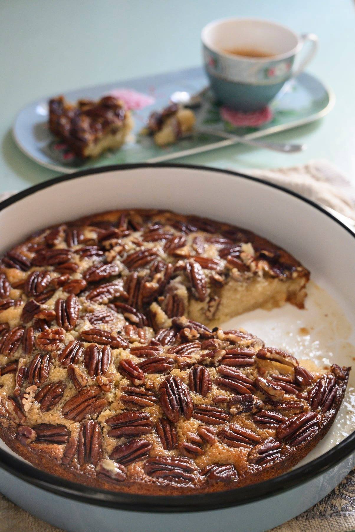 עוגת אגוזי פקאן ושמן זית, עדיין בתבנית עם פרוסה אחת שכבר חסרה – הוכחה שסבלנות היא לא אחת ממעלותיי