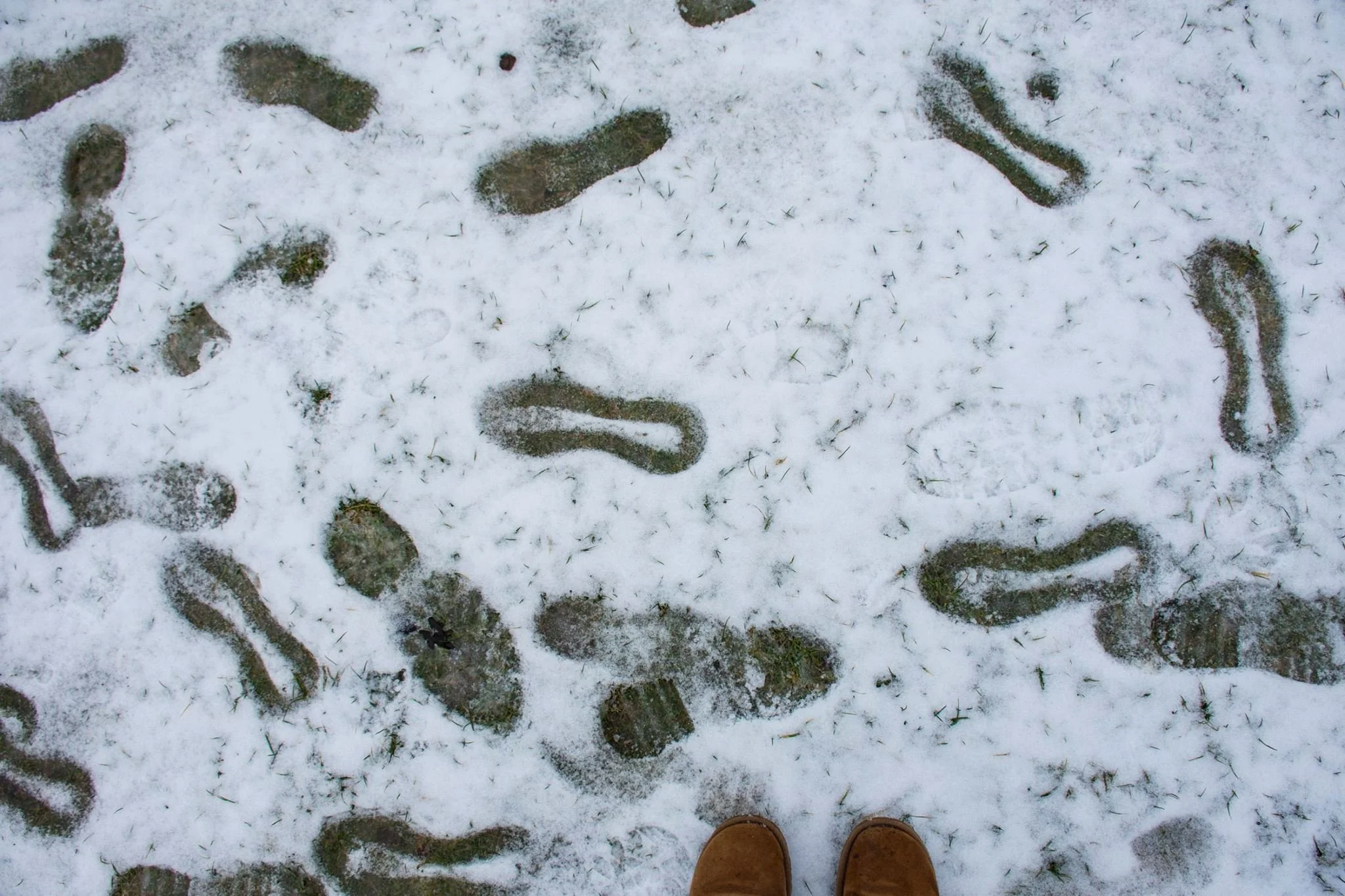 עקבות רגליים מפוזרות בשלג טרי עם מגפי החום של הצלמת בתחתית הפריים, חורף בברלין