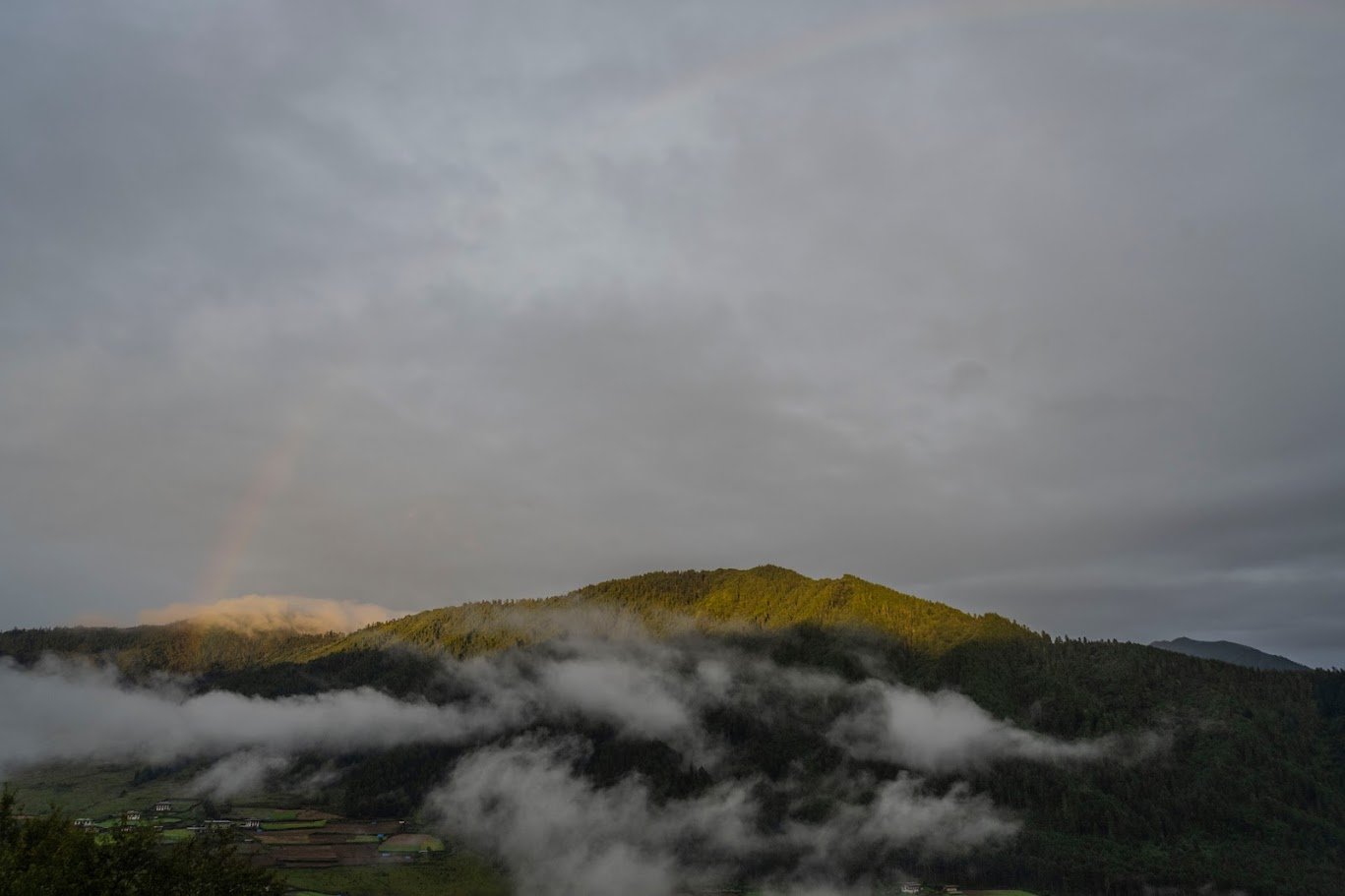 קשת בענן מעל הרים ירוקים ועמק מלא ערפל בוקר – בהוטן, הרי ההימלאיה