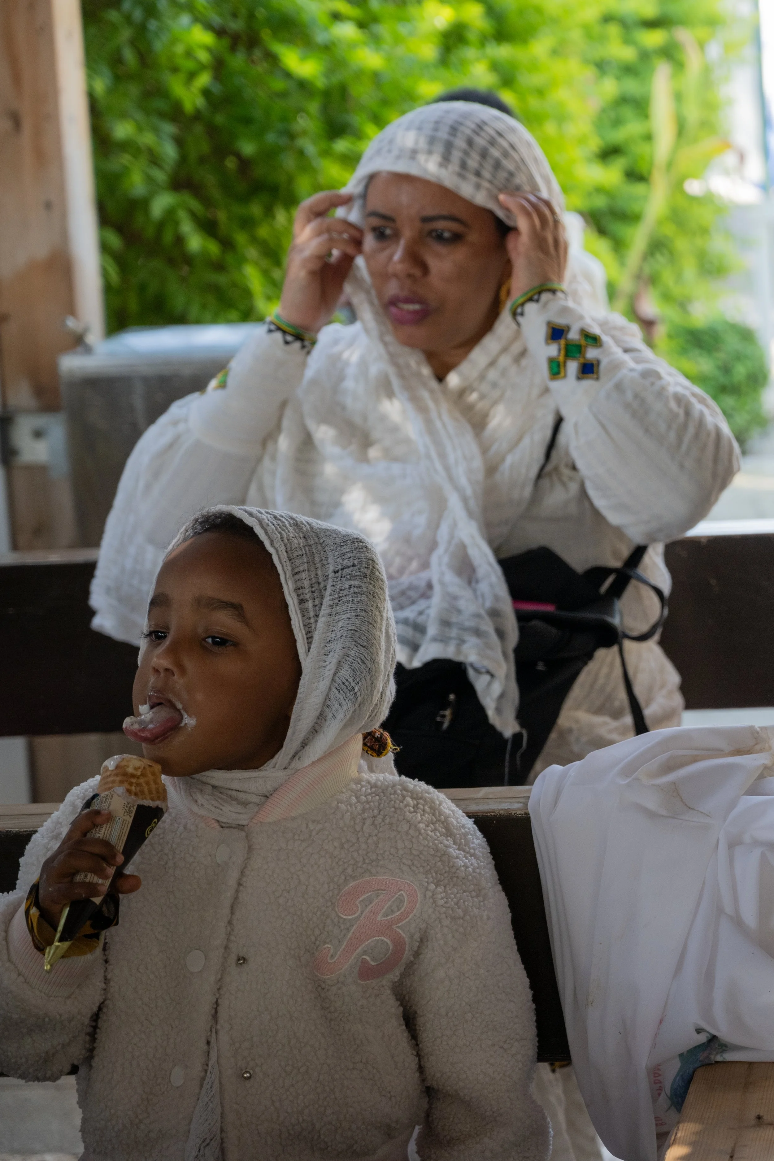 Child eating ice cream, her mother watching over her