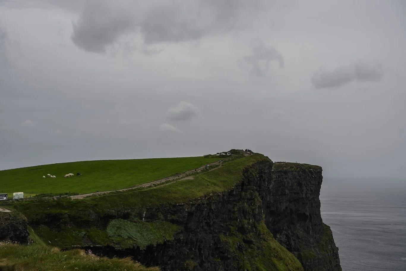 מצוק ירוק תלול נופל אל ים אפור תחת שמיים כבדים – צוקי מוהר, אירלנד