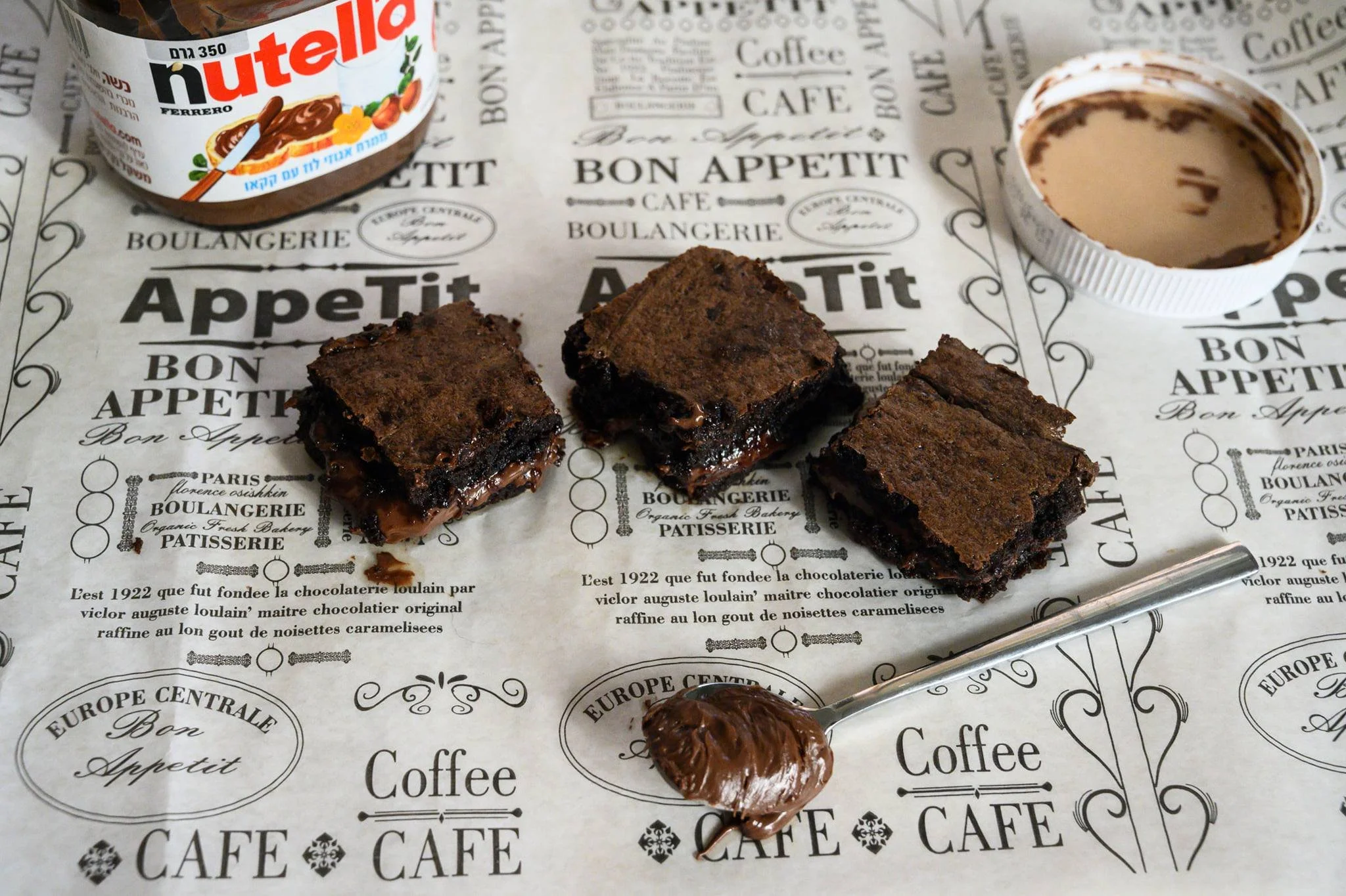 בראוניז נוטלה על נייר קפה, מרכז רך ונוזלי וכפית בצד, כי לטעום תוך כדי צילום זה בהחלט חלק מהעבודה