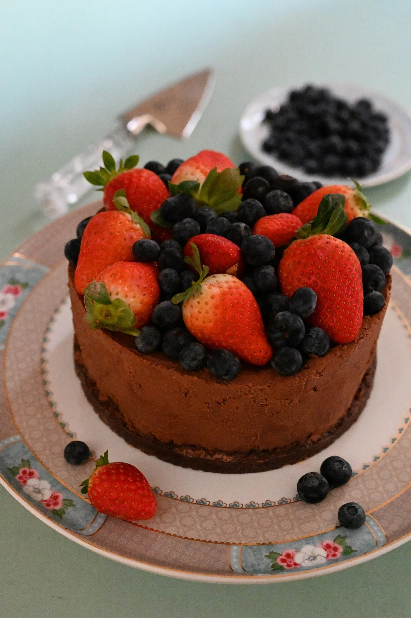 עוגת מוס שוקולד ביתית עמוסה בתותים ואוכמניות, מחכה לפרוסת יום ההולדת הראשונה