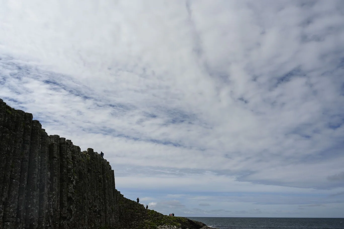 צוקי בזלת משושים נוגעים בים תחת שמיים מעוננים – החוף הצפוני, צפון אירלנד