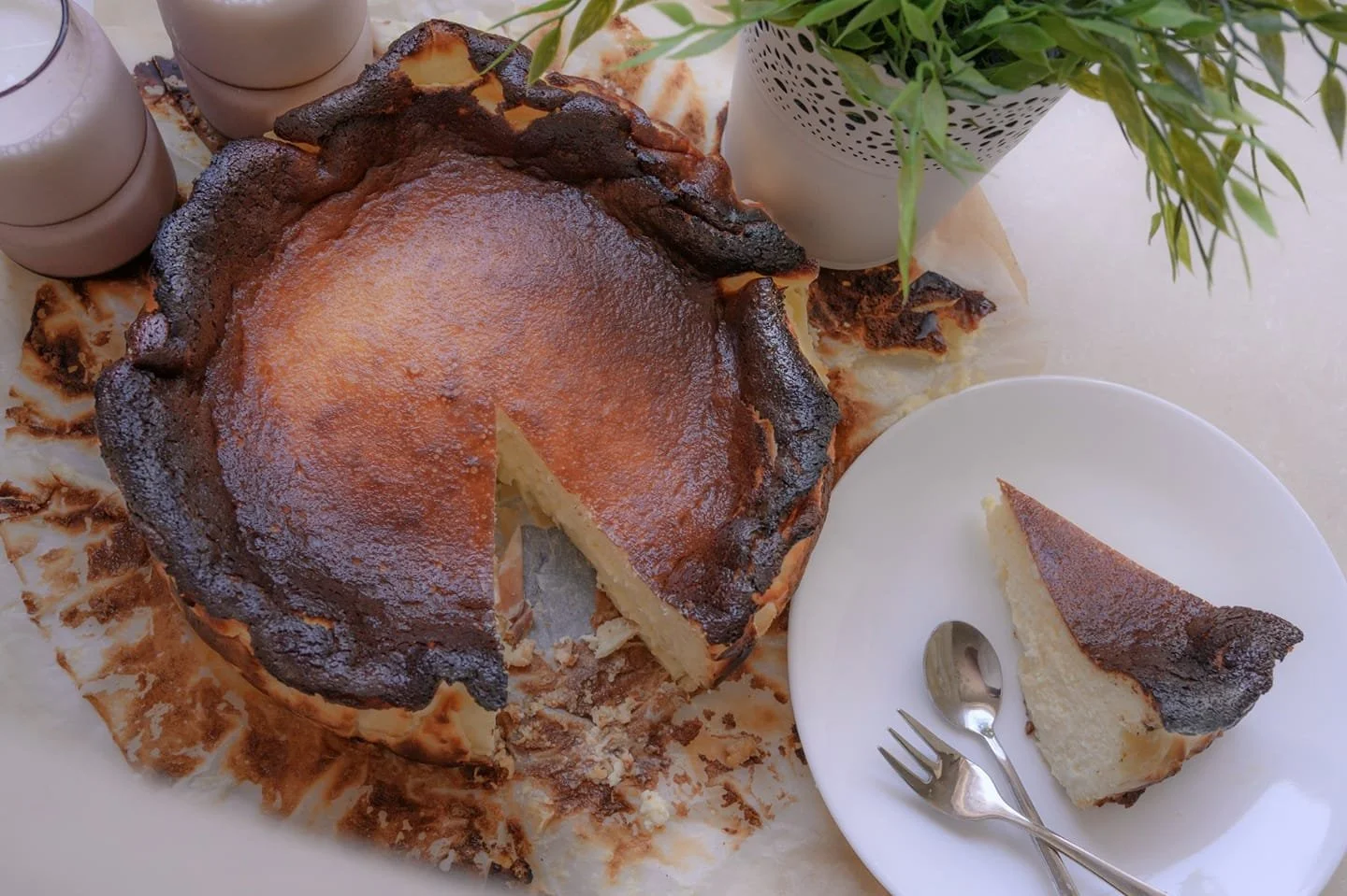 עוגת גבינה באסקית שחומה בקצוות ולבנה מבפנים, הפרוסה הראשונה כבר מוגשת