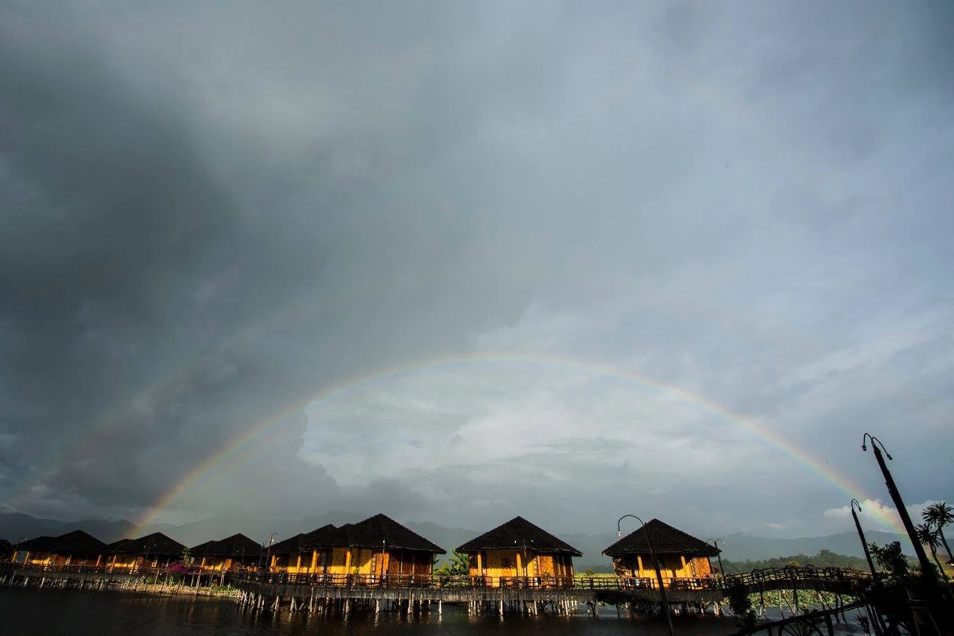 קשת כפולה בשמיים מעל בתי עץ על המים לאחר גשם – אגם אינלה, מיאנמר