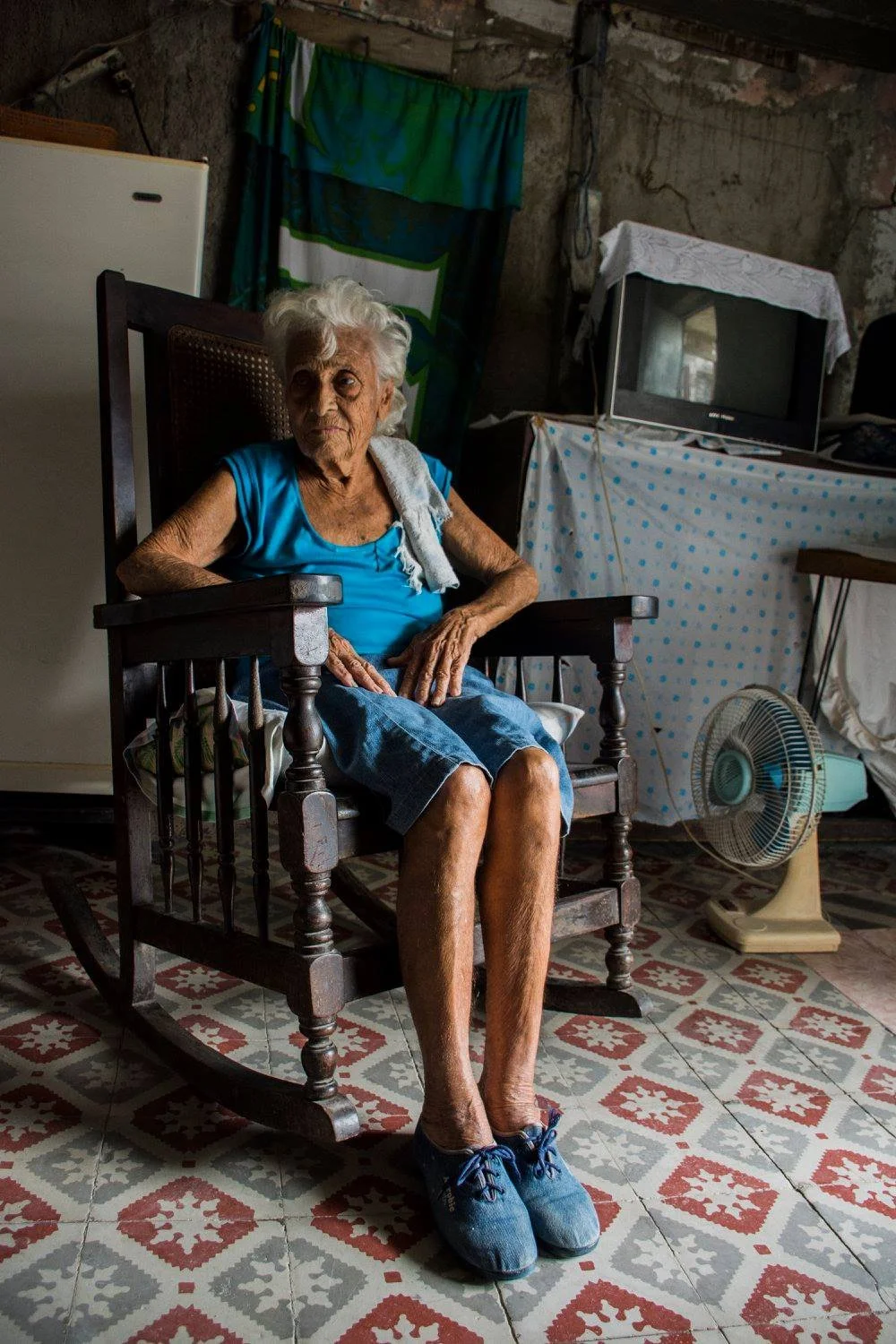 אישה מבוגרת יושבת בכיסא נדנדה על רצפת אריחים צבעונית – הוואנה, קובה