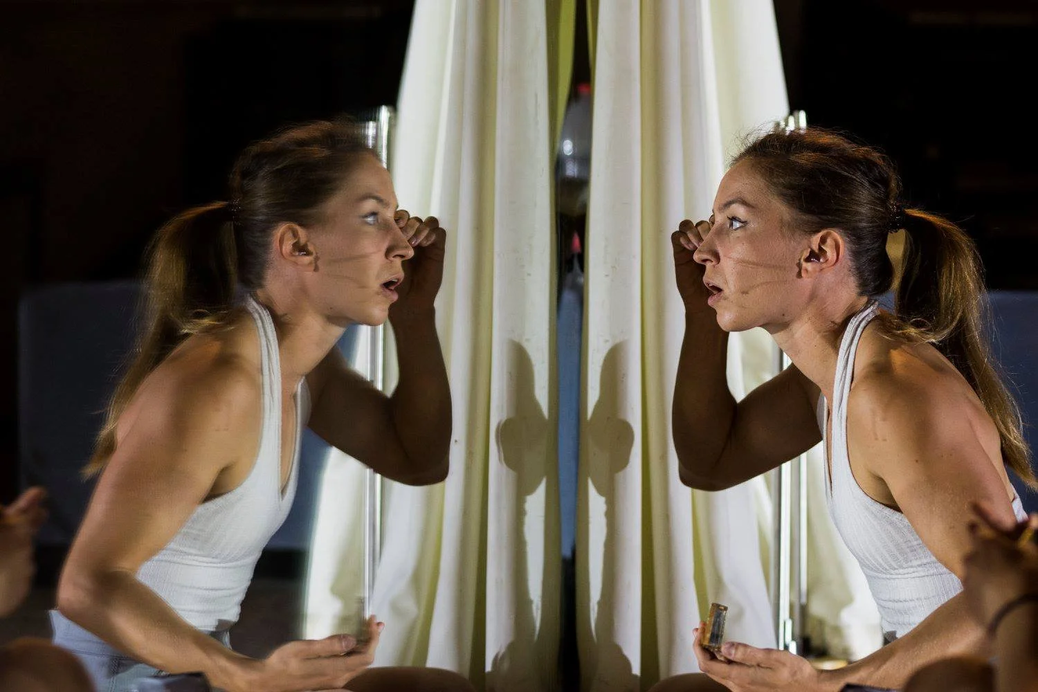 אקרובטית אוויר מתחממת מתחת לזרקור יחיד באולם חשוך